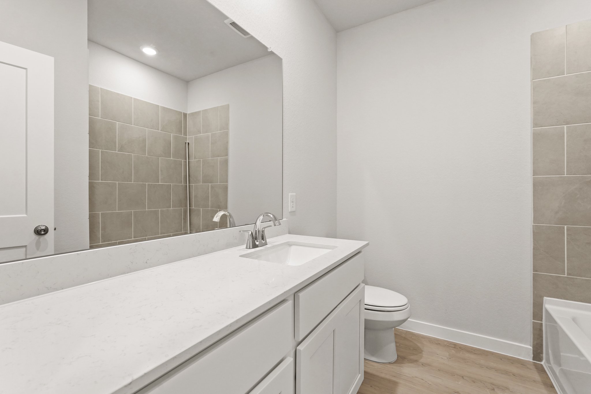 A bathroom with a sink toilet and mirror.