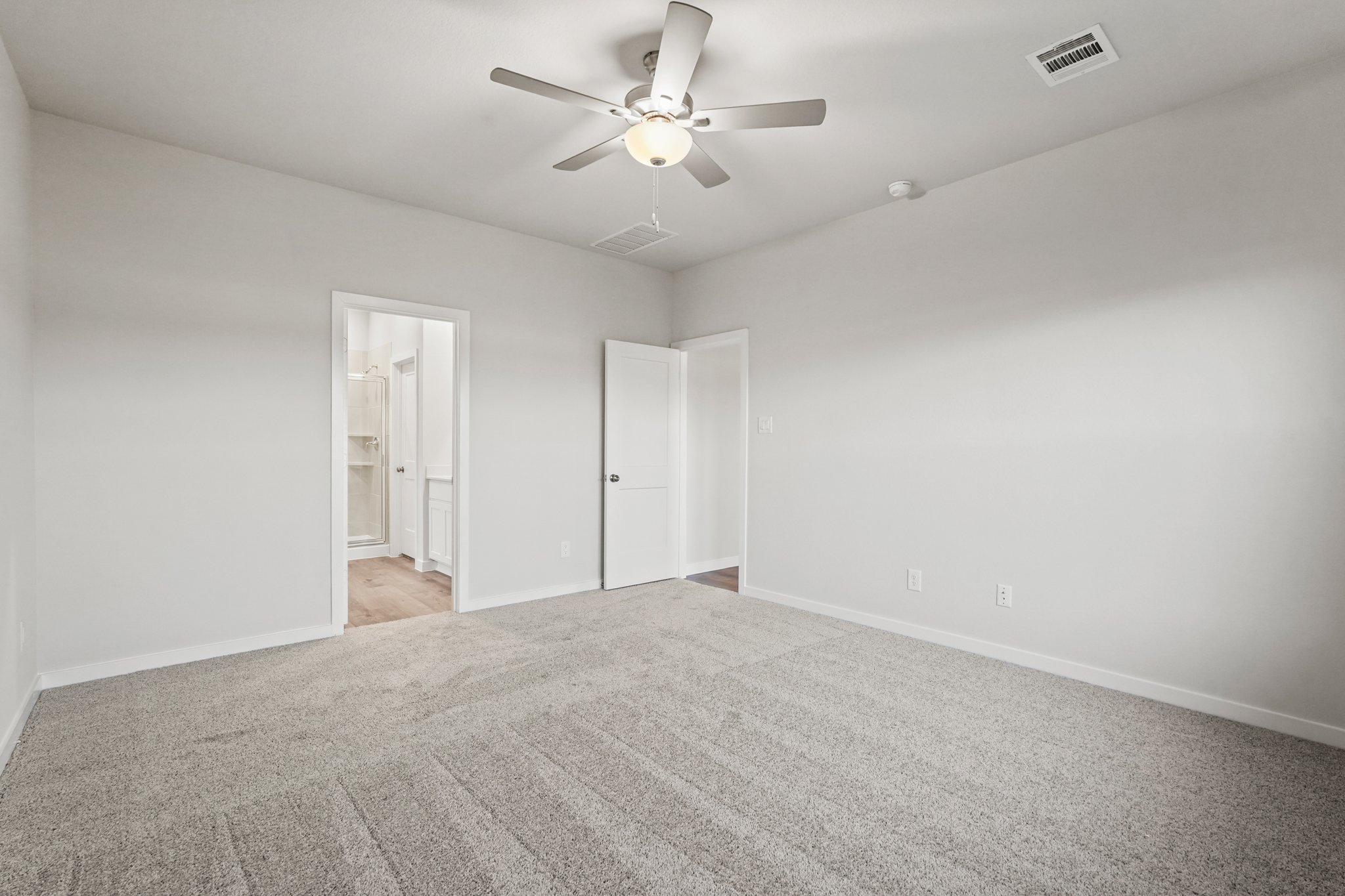 A room with a ceiling fan and a carpet.