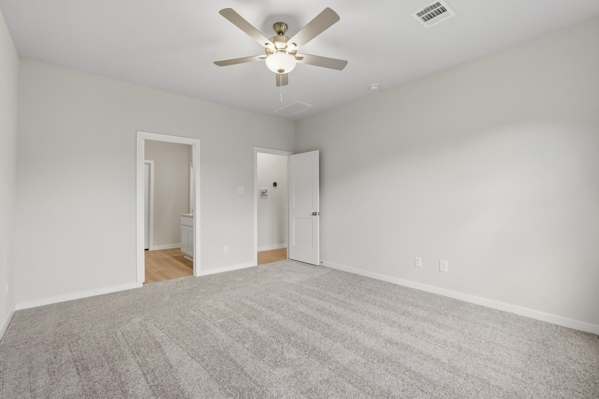 A room with a ceiling fan and carpet.