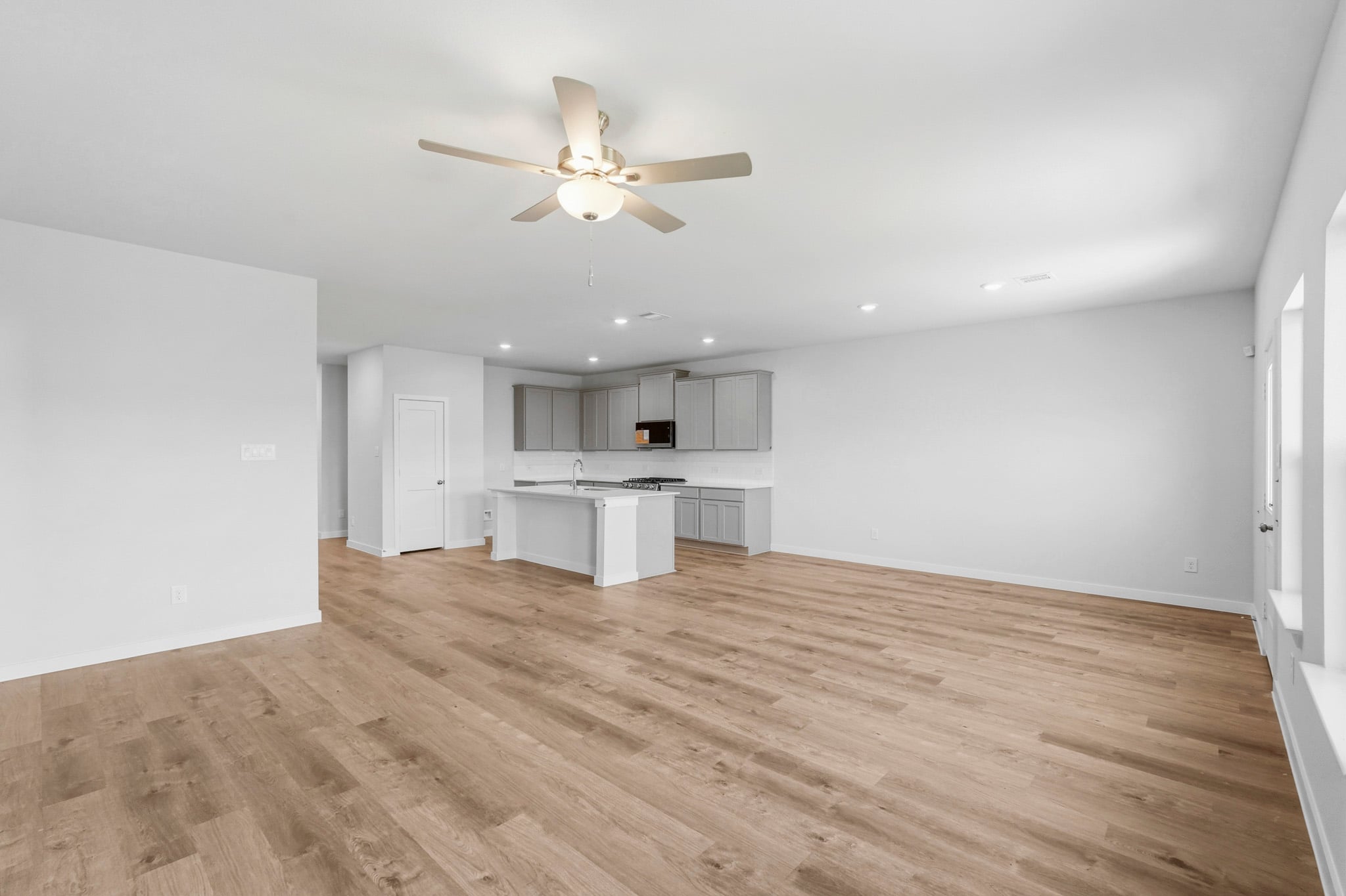 A large empty room with a ceiling fan and a wood floor.