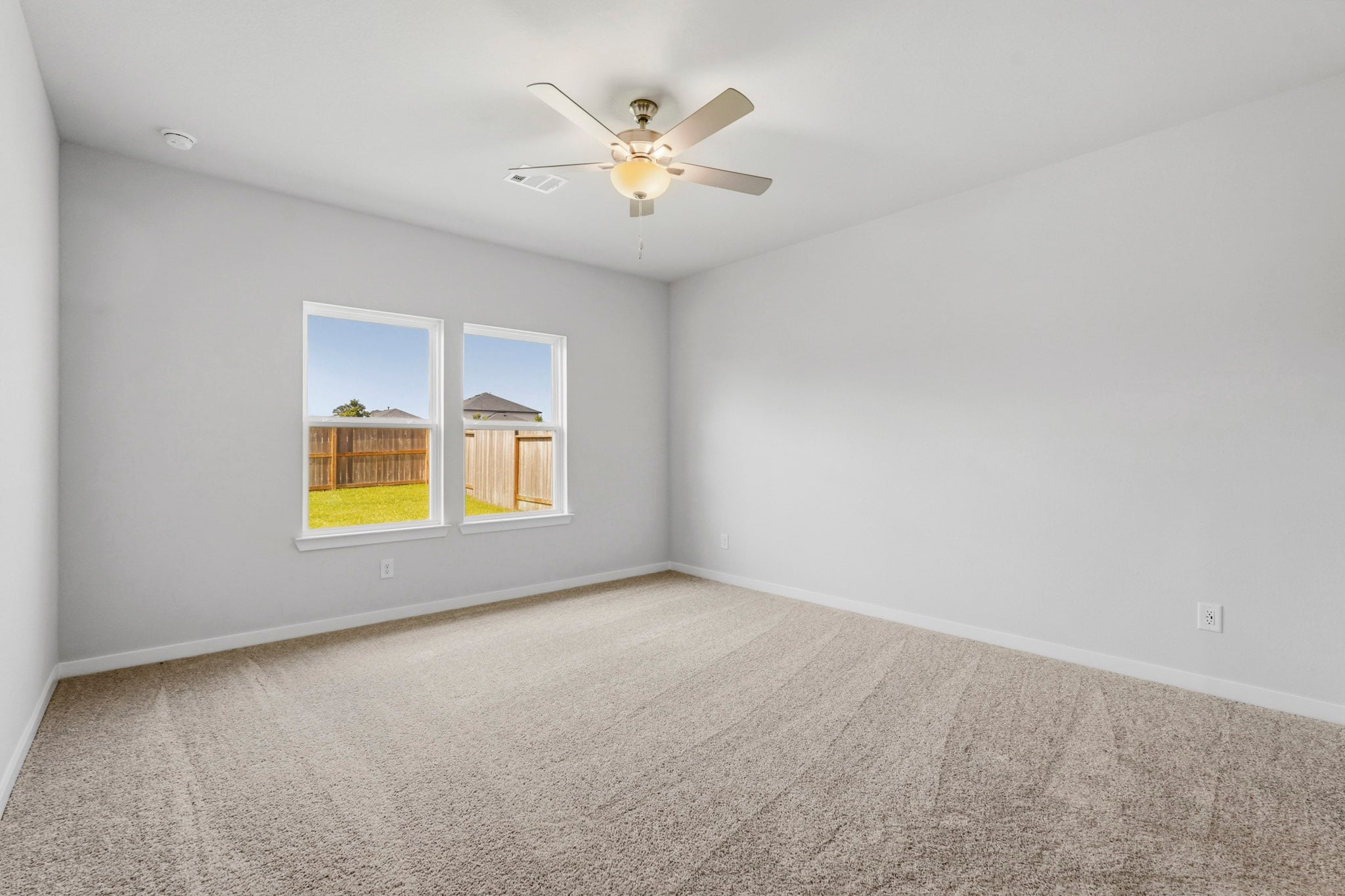 A room with a ceiling fan and a window with a light.