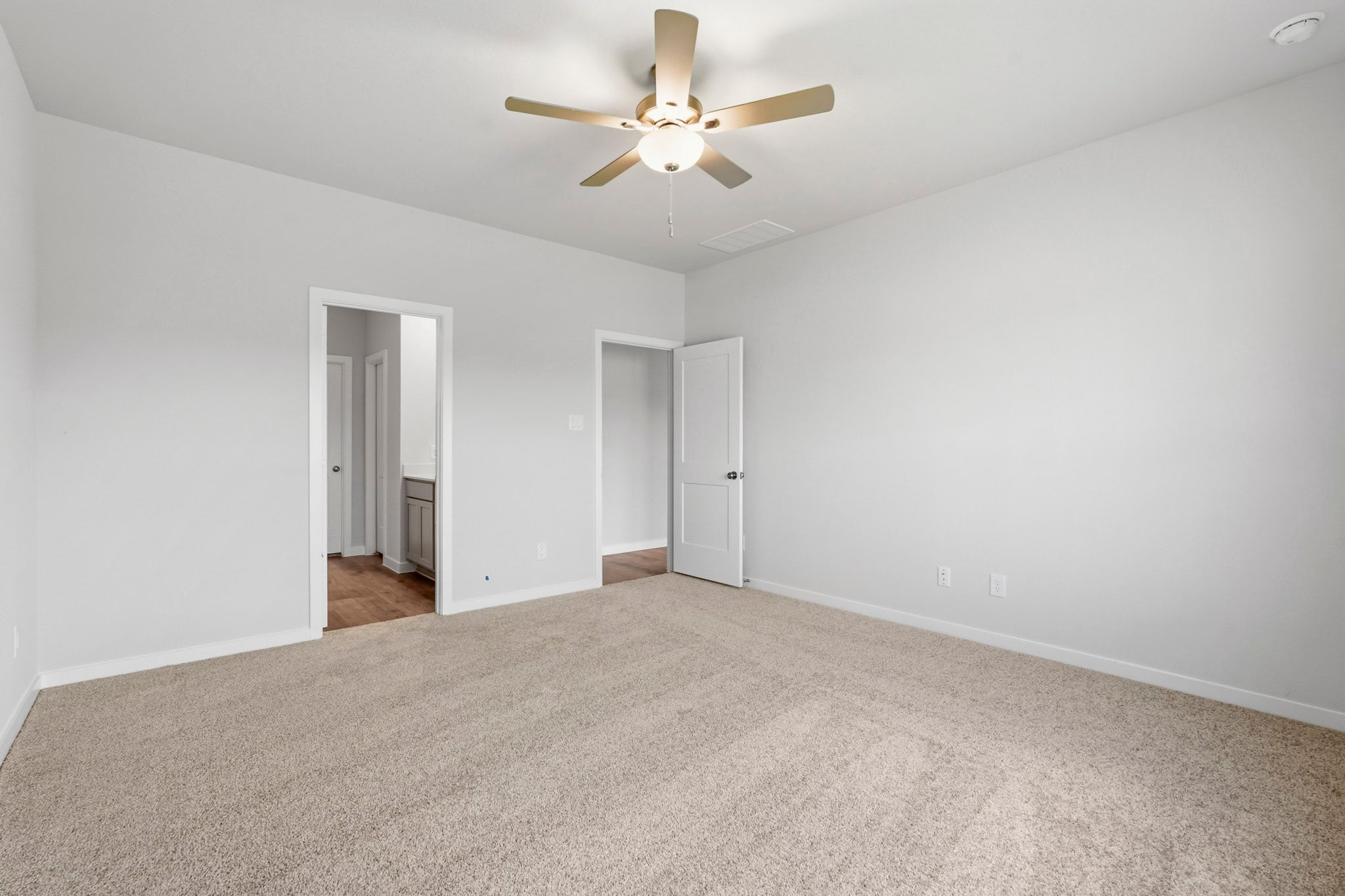 A room with a ceiling fan and a carpet.