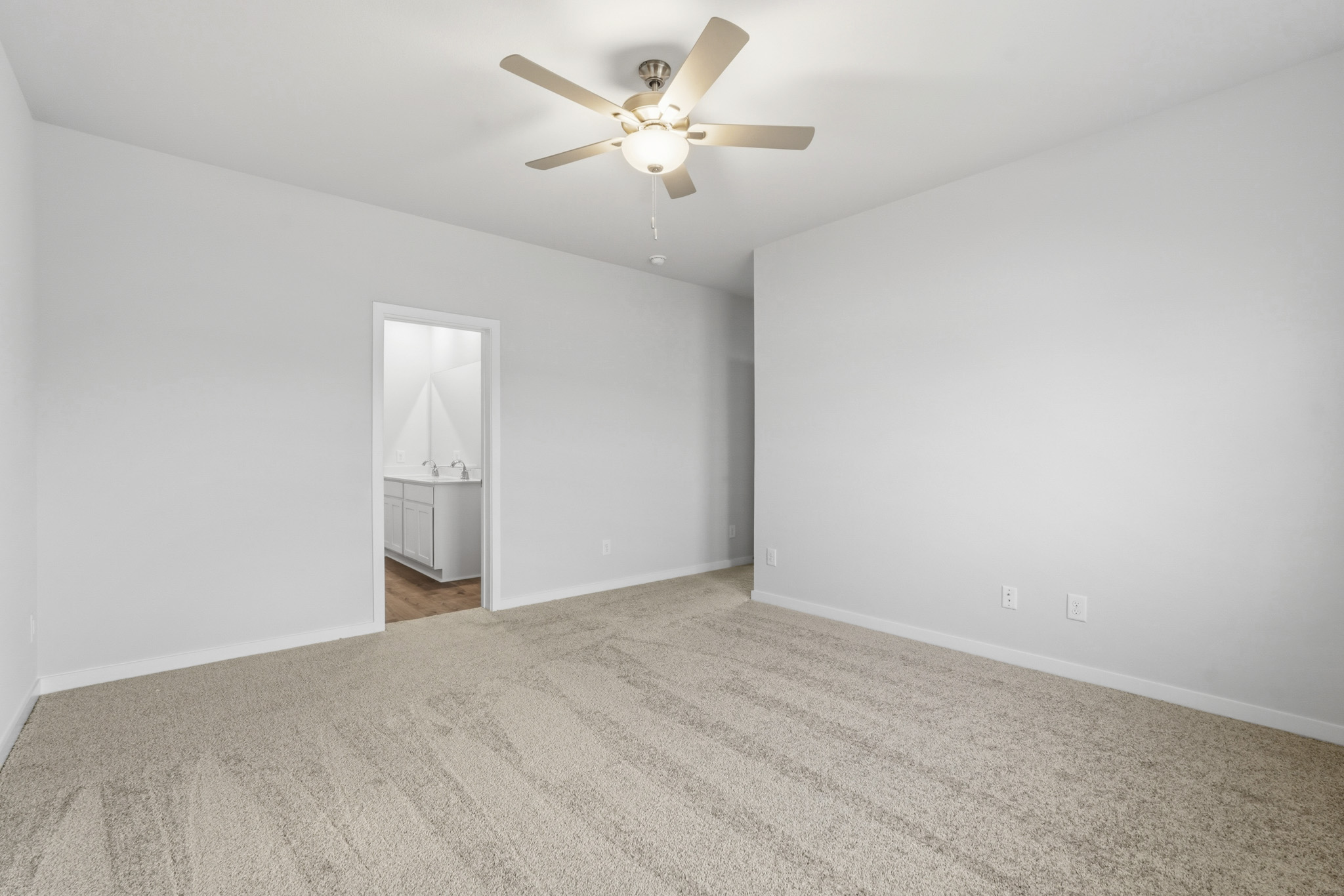 A room with a ceiling fan and a carpet.
