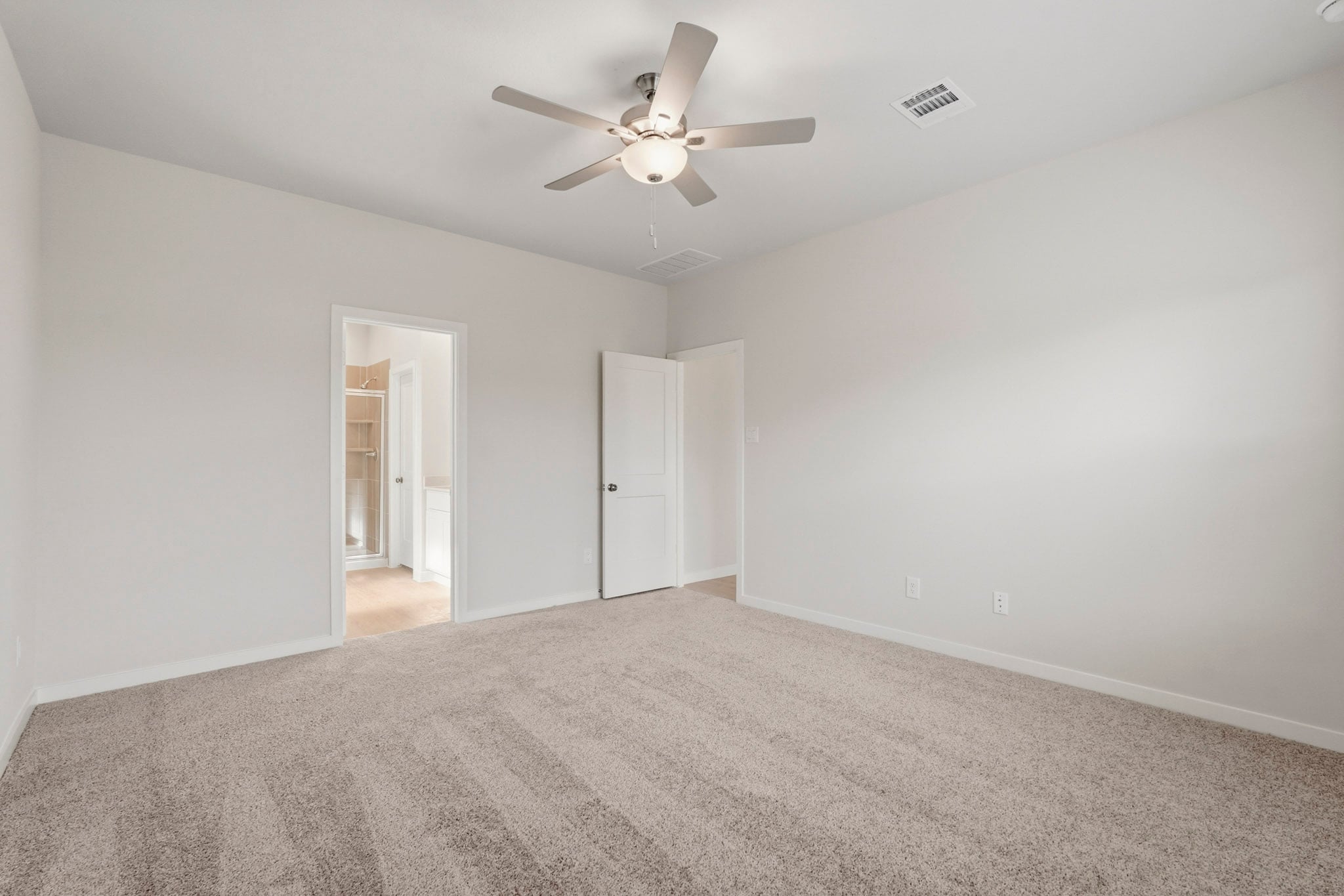 A room with a ceiling fan and a carpet.