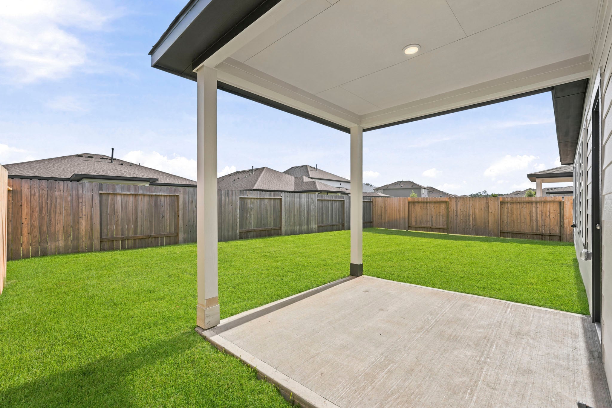 A backyard with a fence and a covered patio.