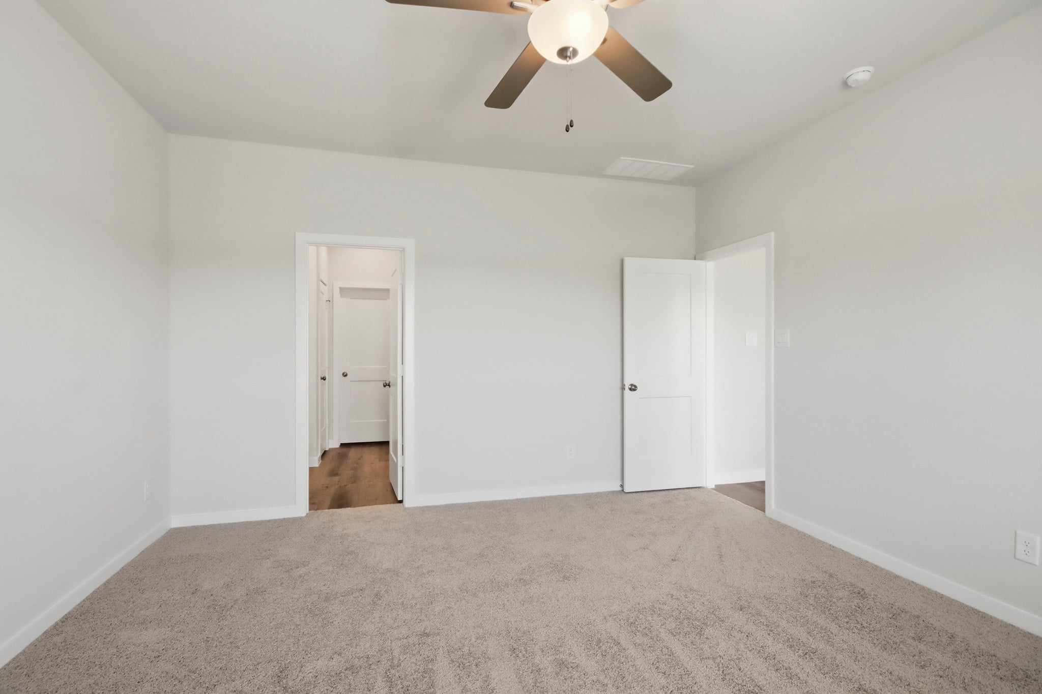 A room with a ceiling fan and white doors.
