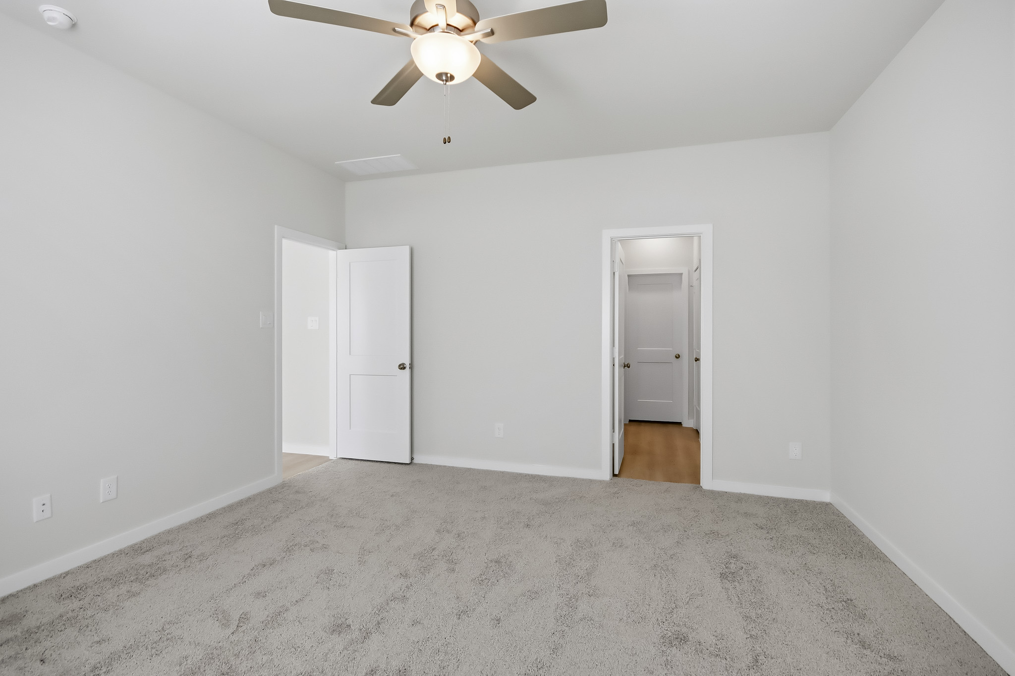 A room with a ceiling fan and a door.