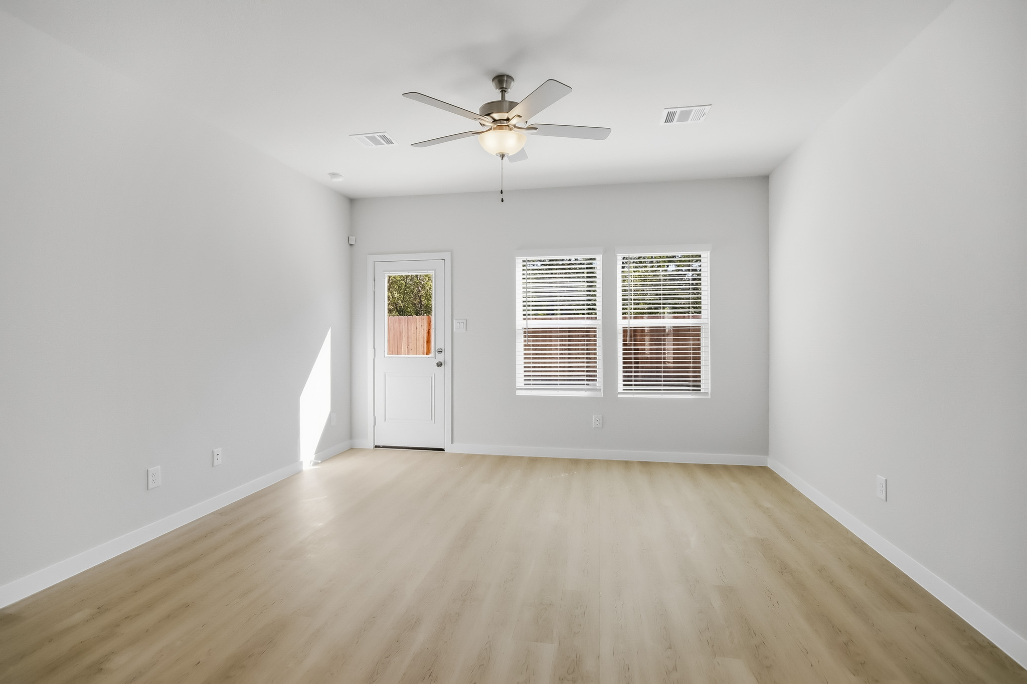 A room with a ceiling fan and a wood floor.