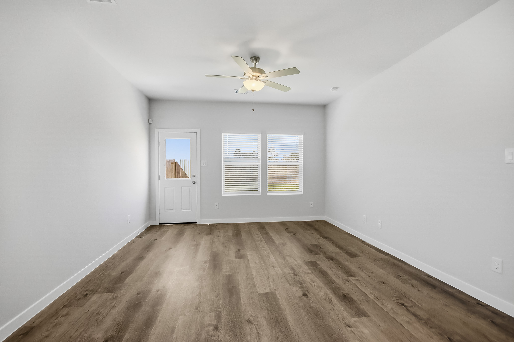A room with a ceiling fan and a wood floor.