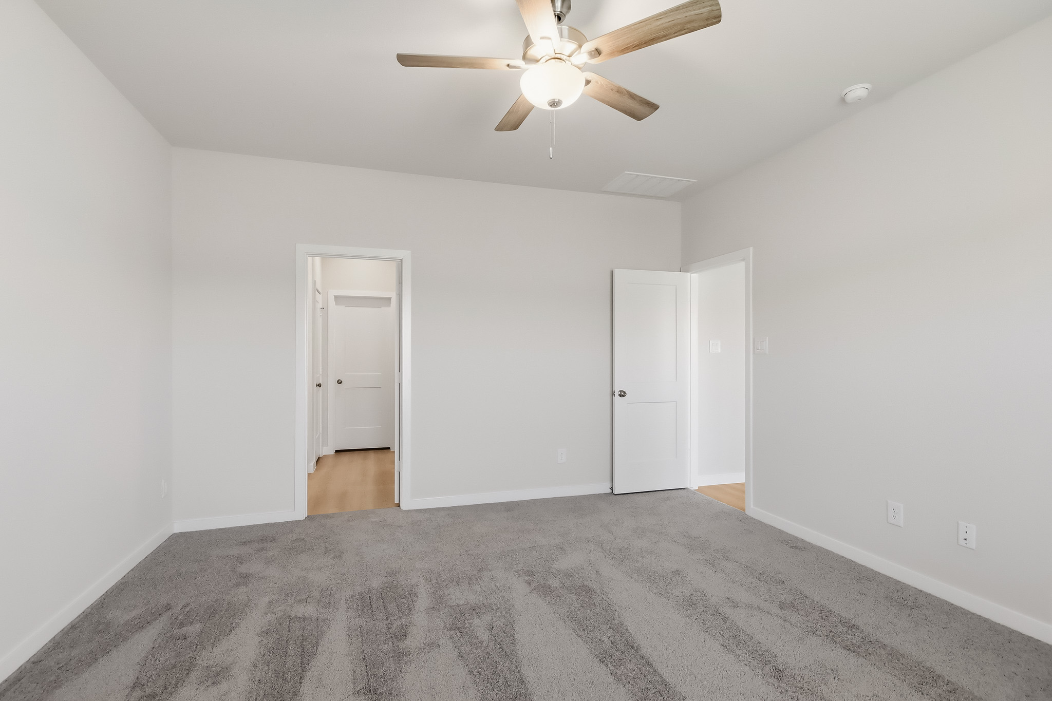A room with a ceiling fan and white walls.