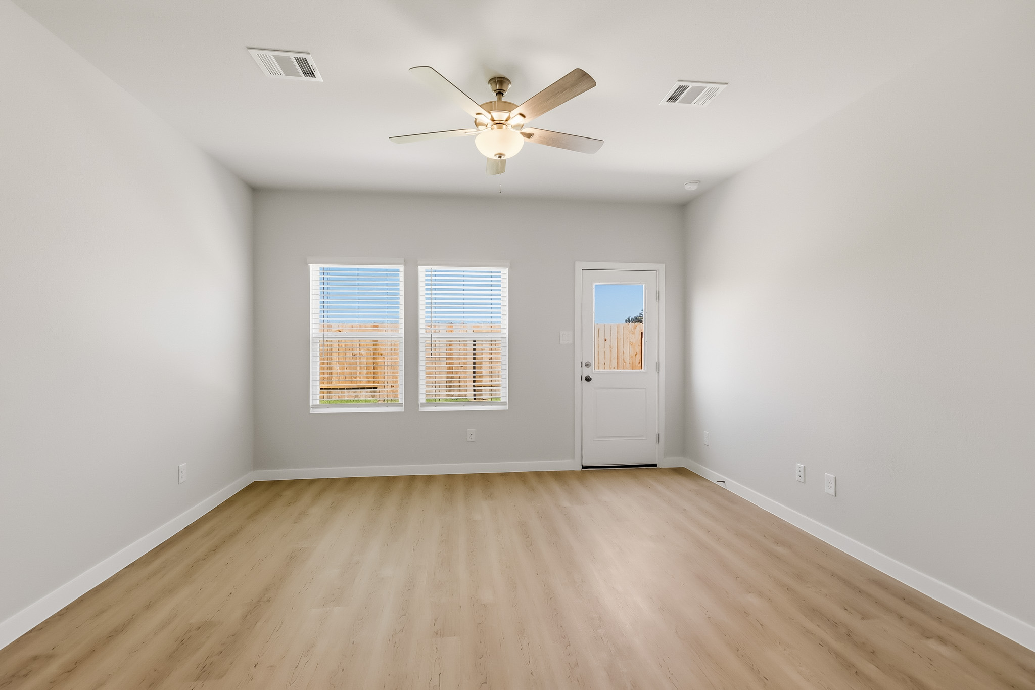 A room with a ceiling fan and a wood floor.
