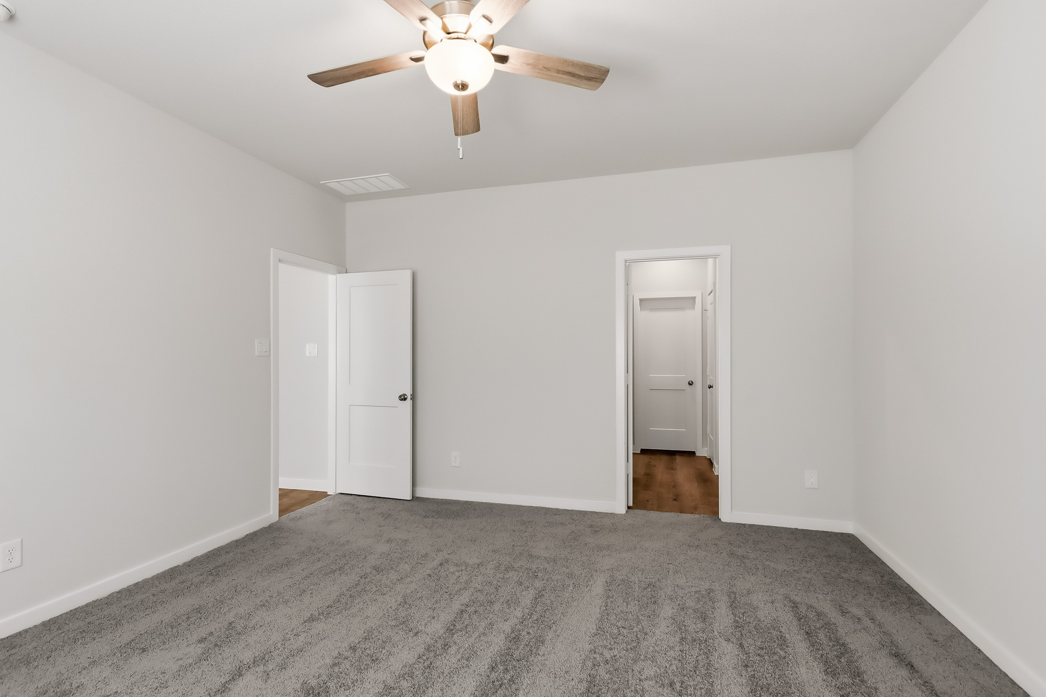 A room with a ceiling fan and white doors.