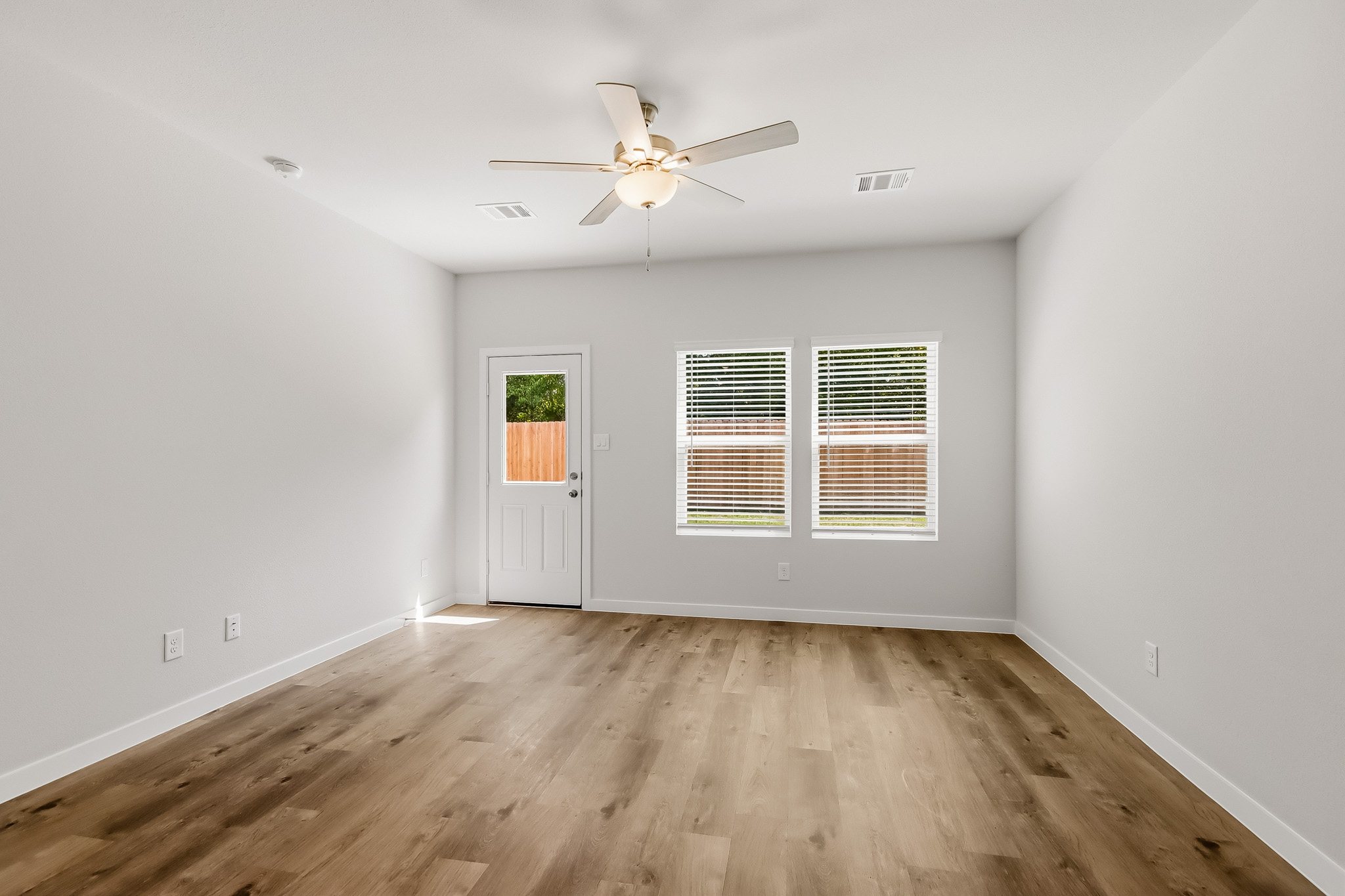 A room with a ceiling fan and a wood floor.