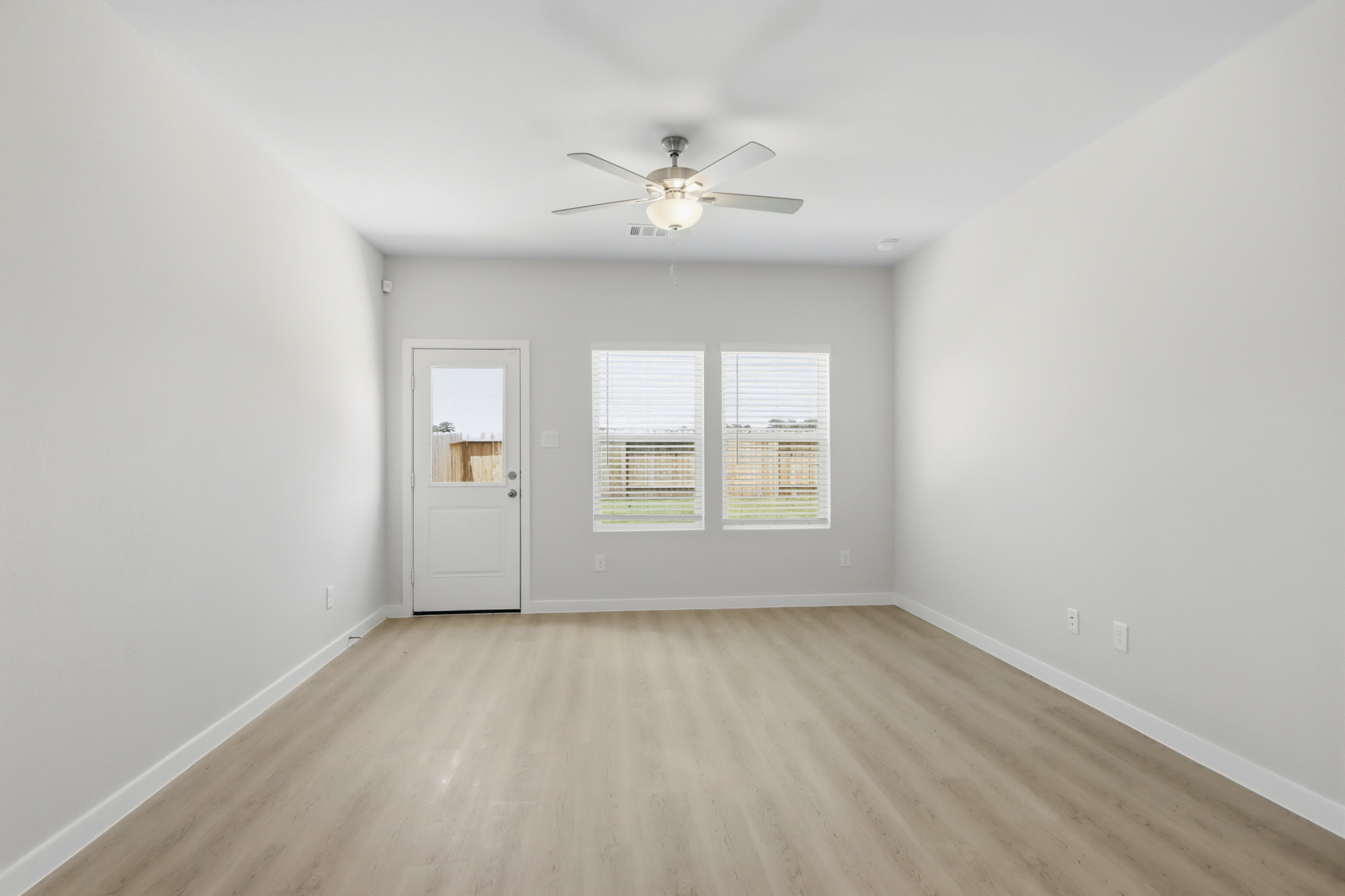 A room with a ceiling fan and a wood floor.