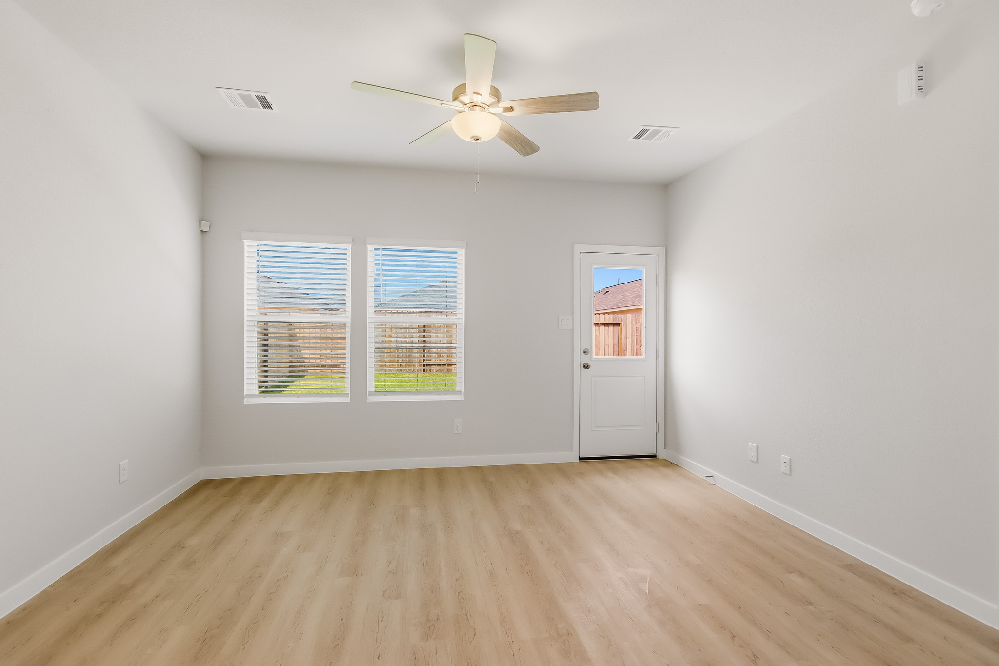 A room with a ceiling fan and a wood floor.