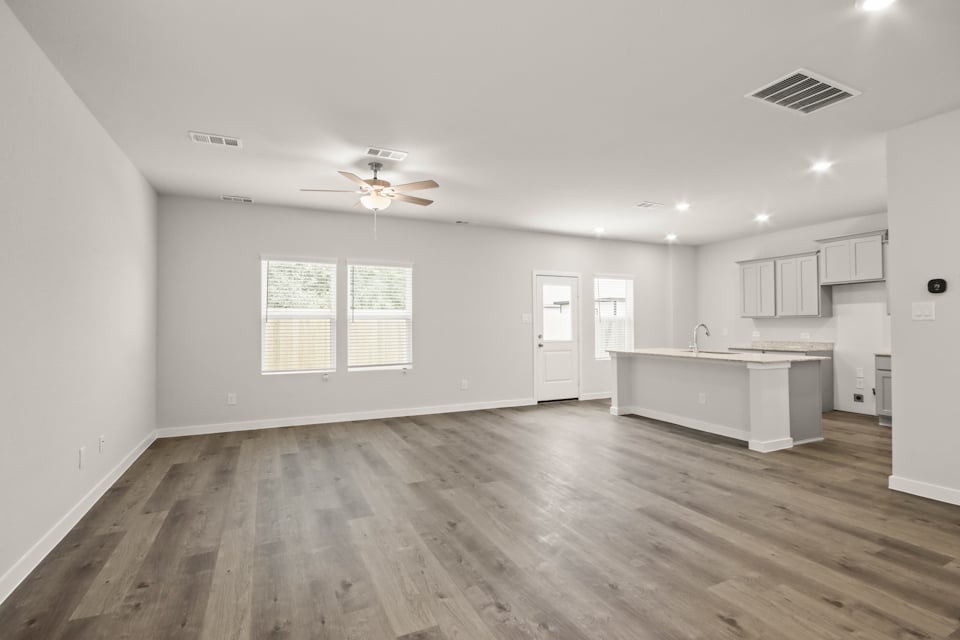A large empty room with a wood floor and a white counter top.