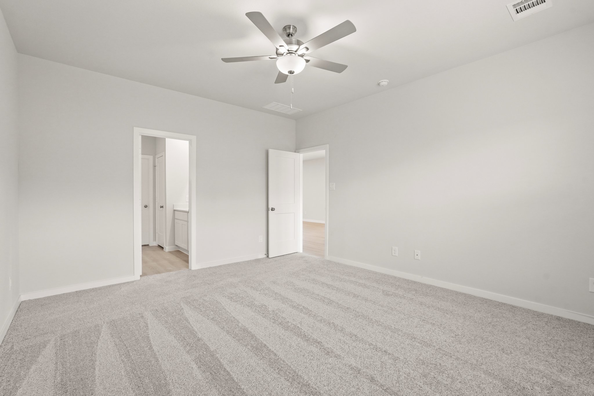 A room with a ceiling fan and a carpet.