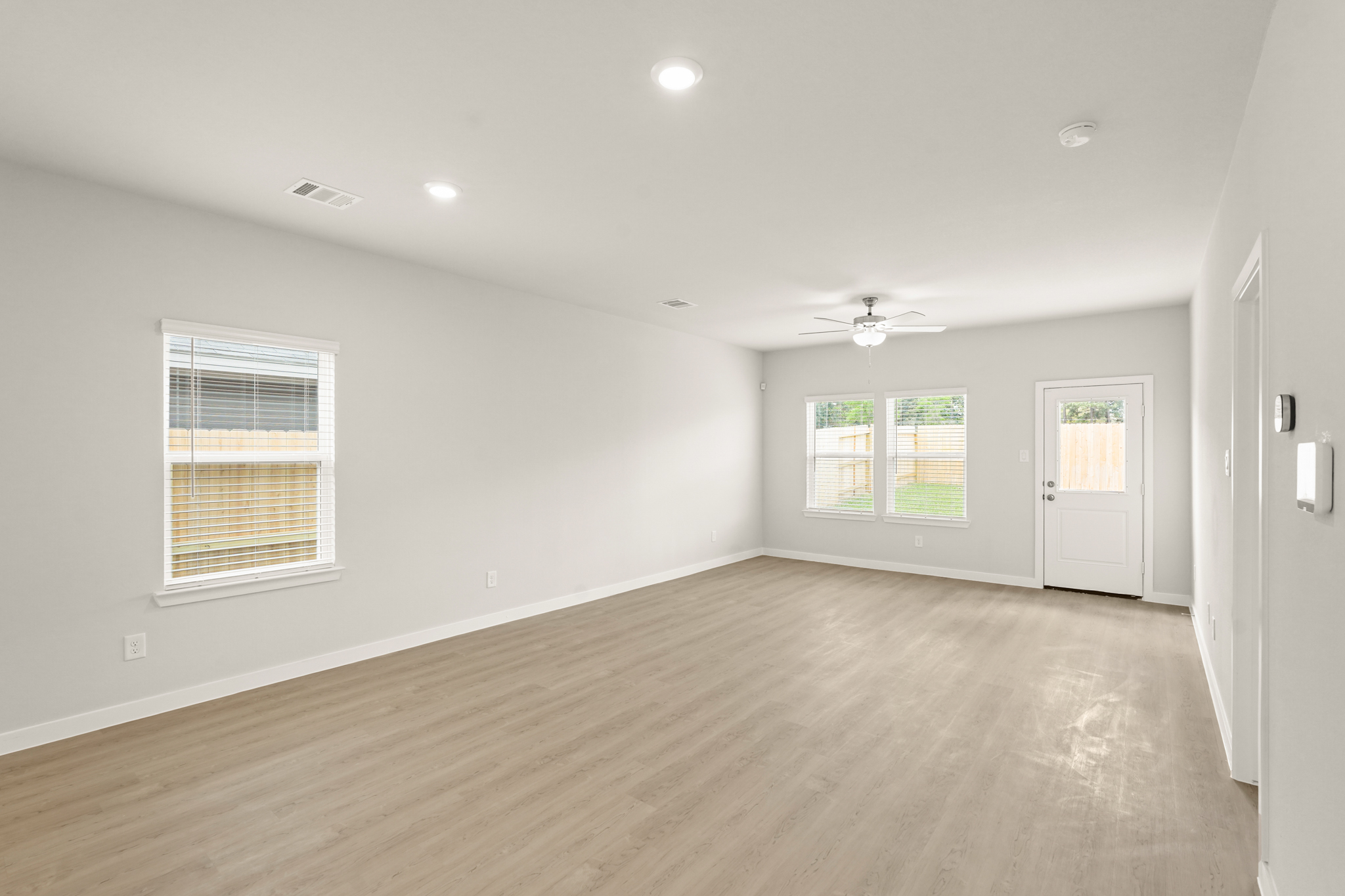A room with a wood floor and a wood floor with a ceiling fan.