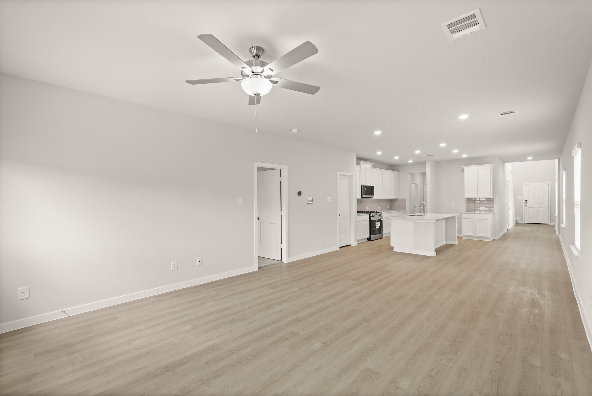 A large empty room with a ceiling fan and a wood floor.