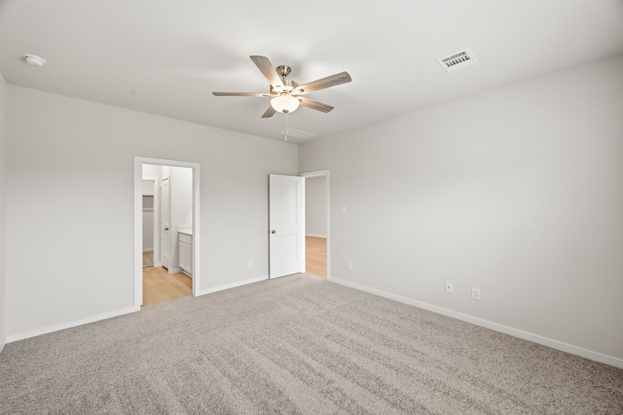 A room with a ceiling fan and carpet.