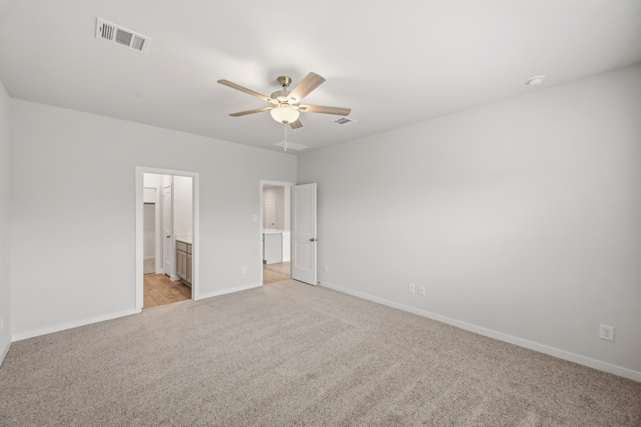 A room with a ceiling fan and carpet.