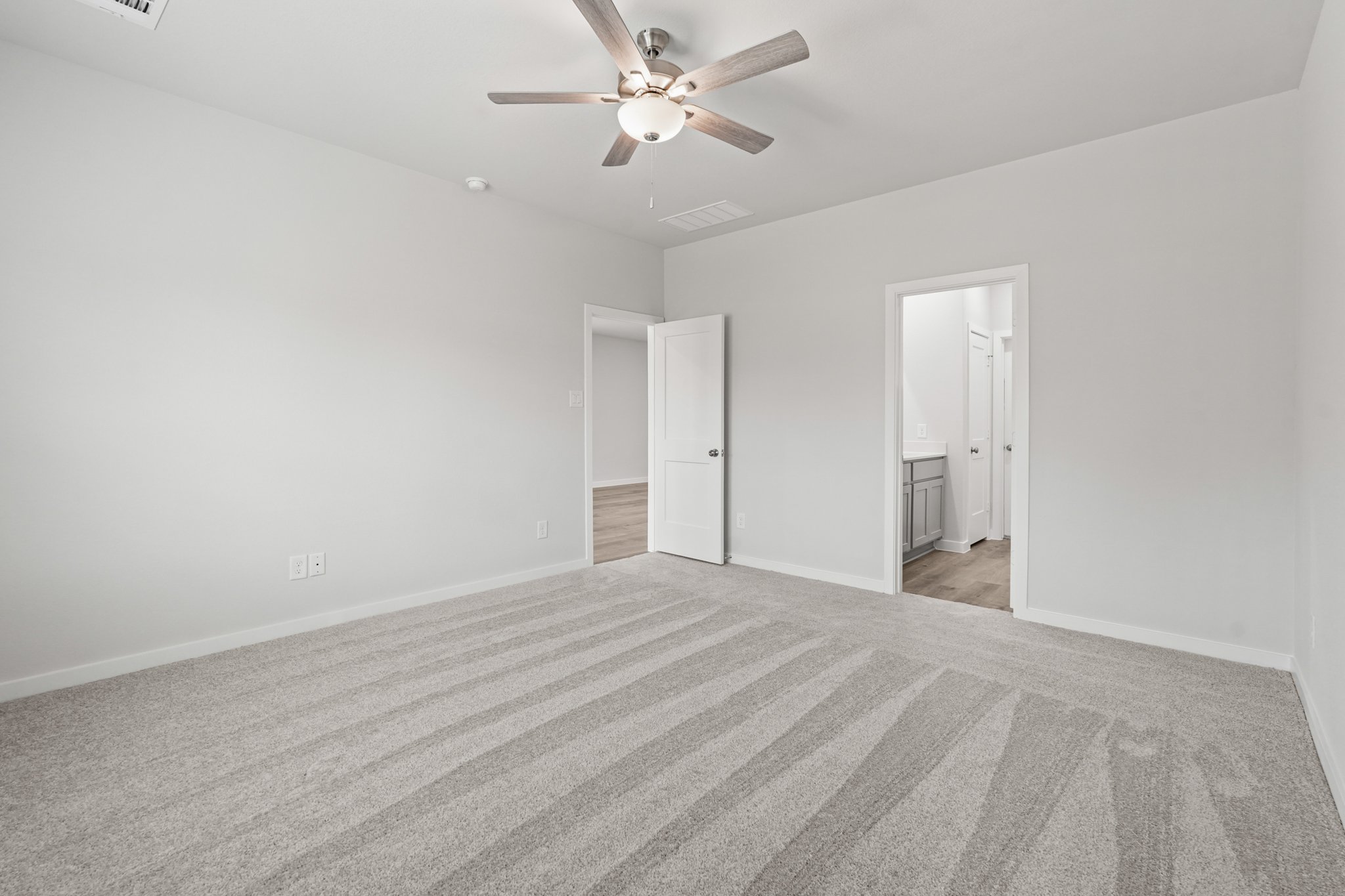 A room with a ceiling fan and a carpet.