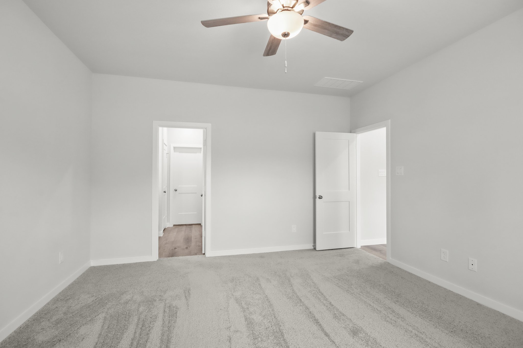 A room with a ceiling fan and white doors.