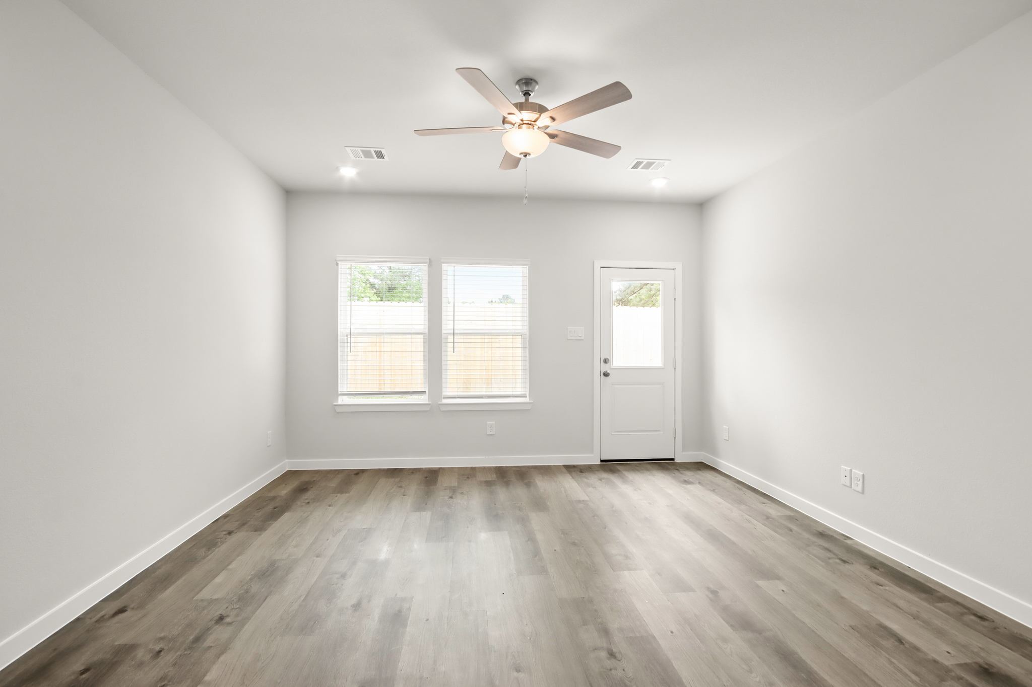 A room with a ceiling fan and a wood floor.