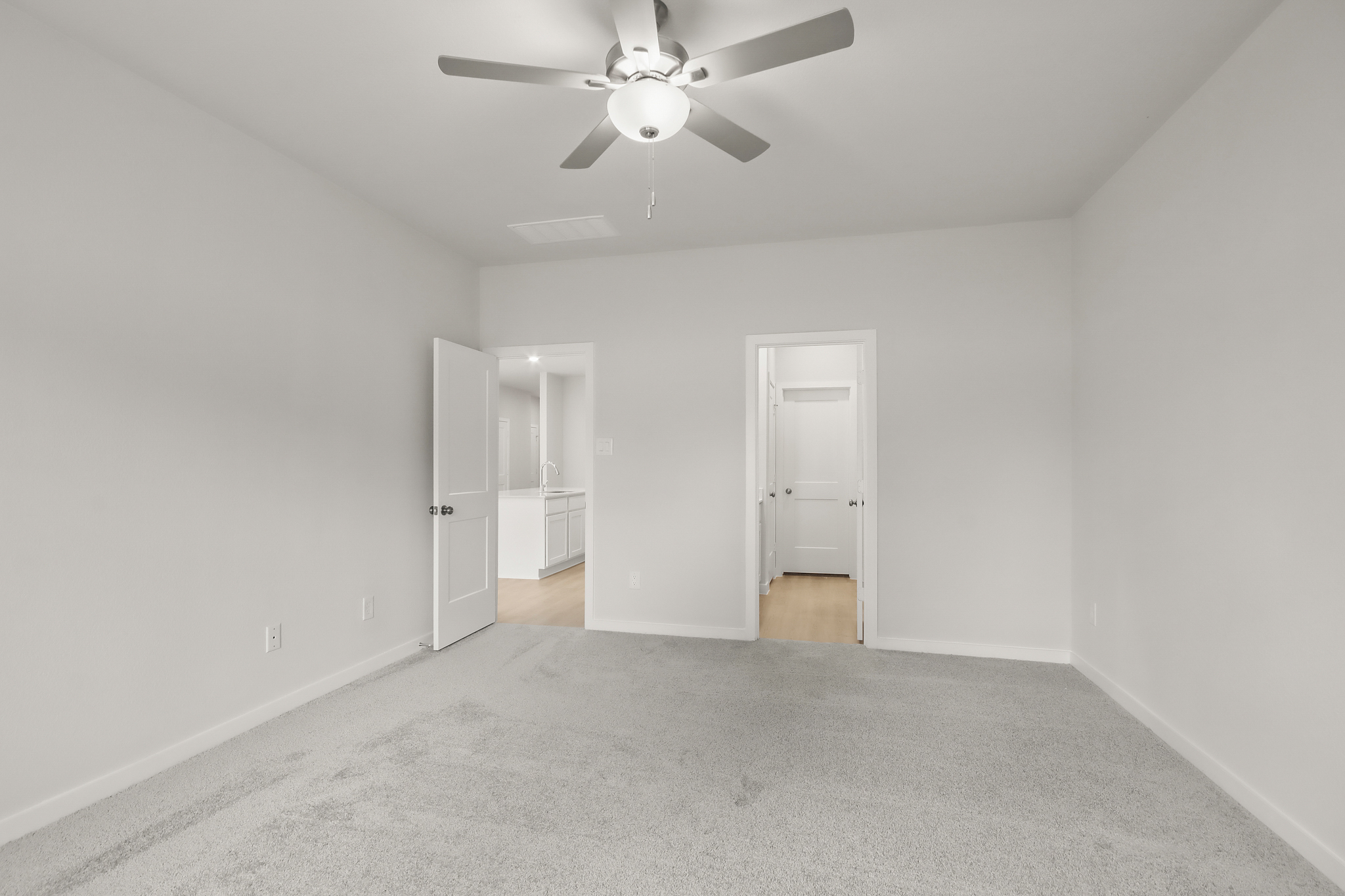 A room with a ceiling fan and a door.