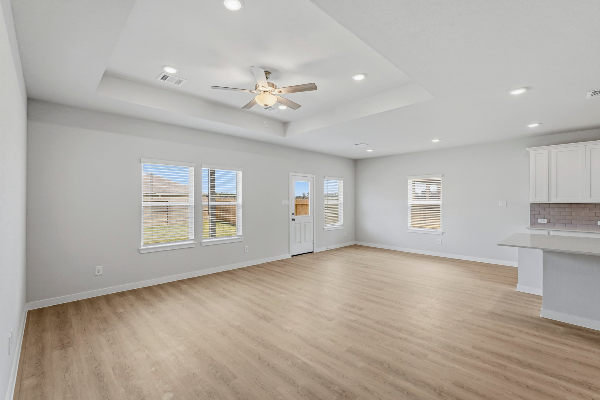 A large empty room with a ceiling fan and a wood floor.