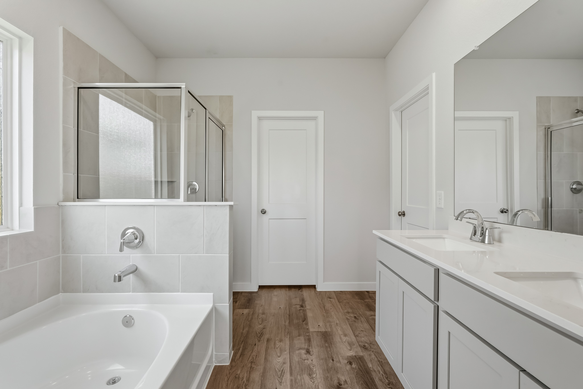 A bathroom with a tub sink and mirror.