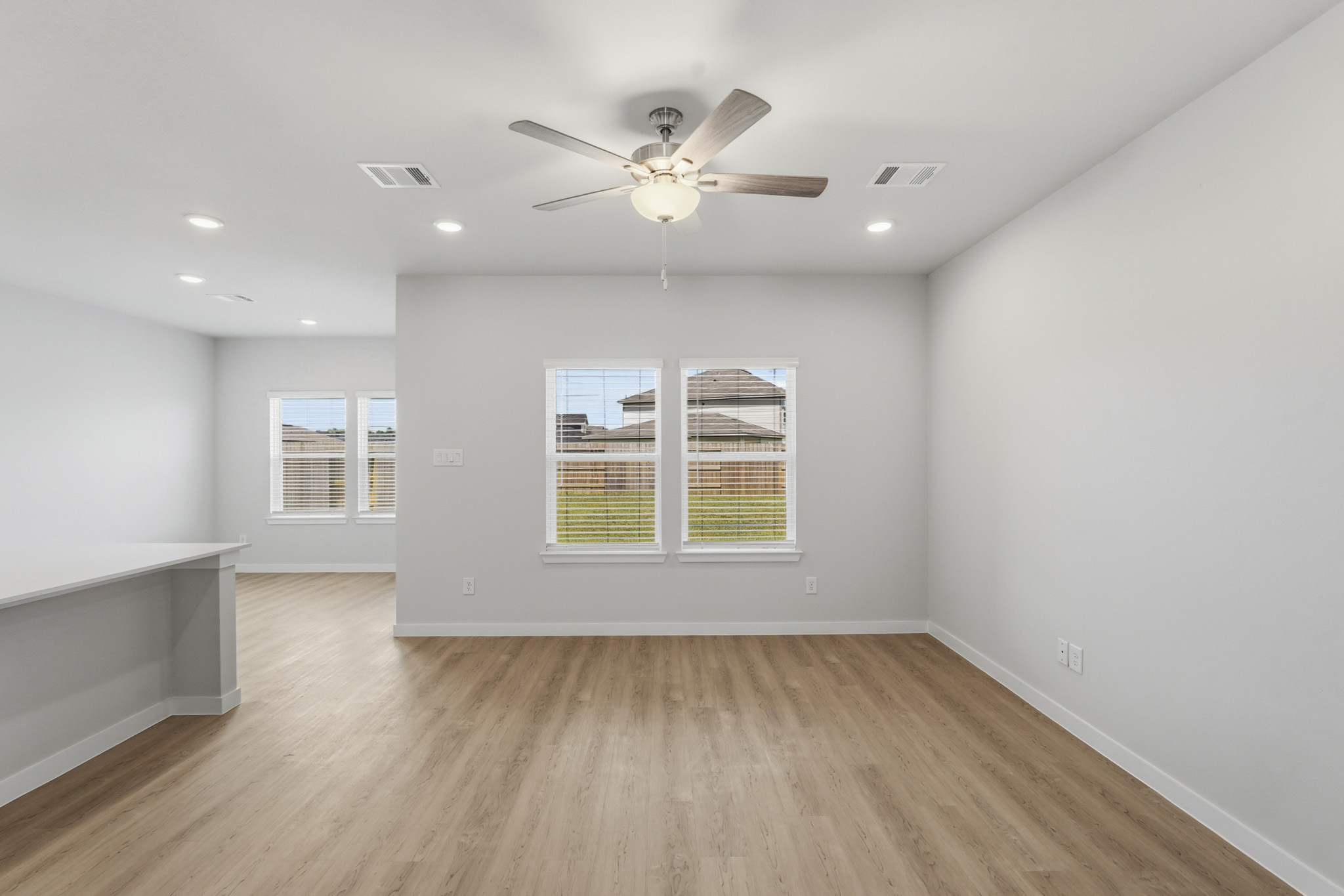 A room with a ceiling fan and a wood floor.
