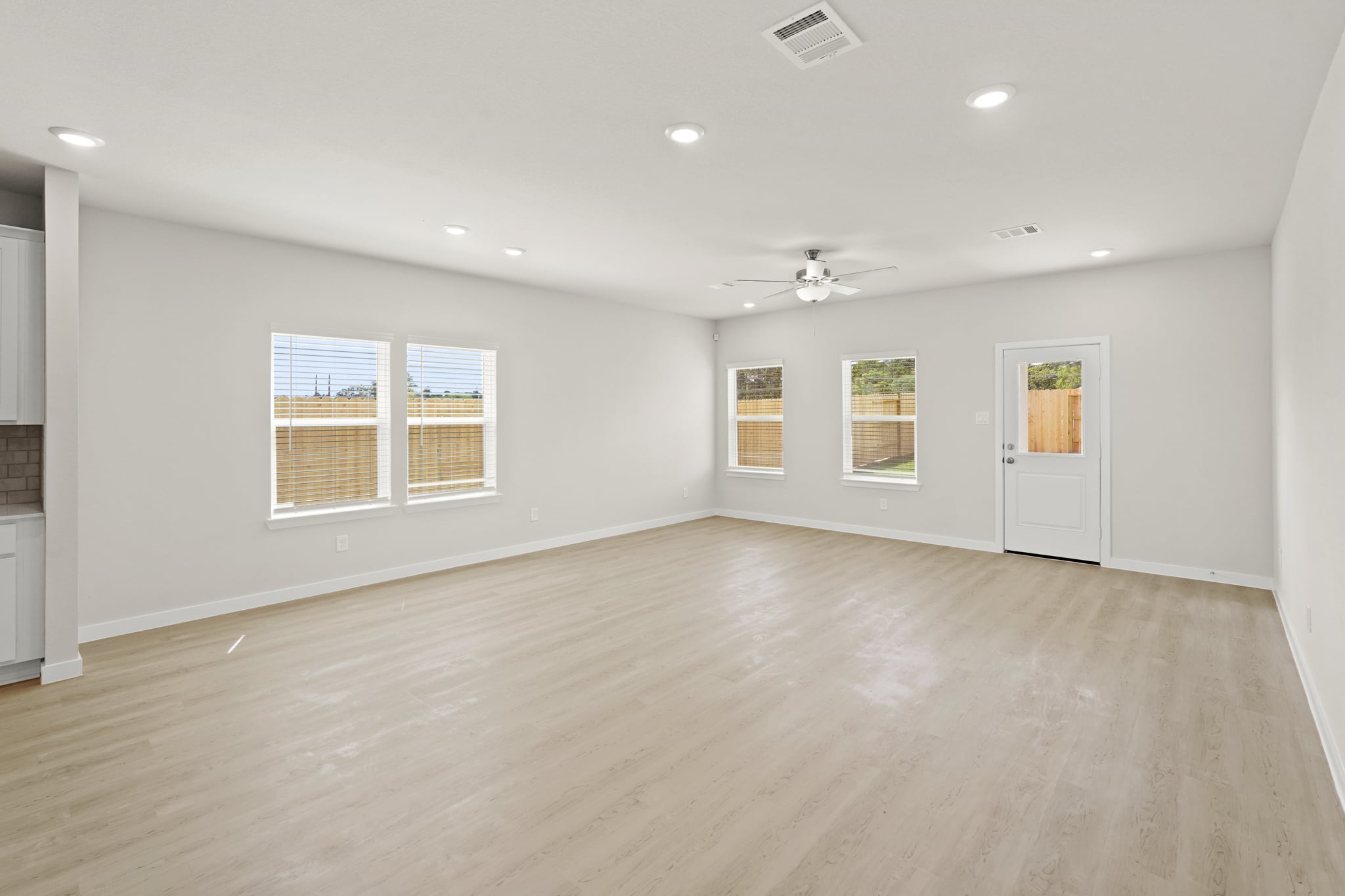 A large empty room with a wood floor and a white door.