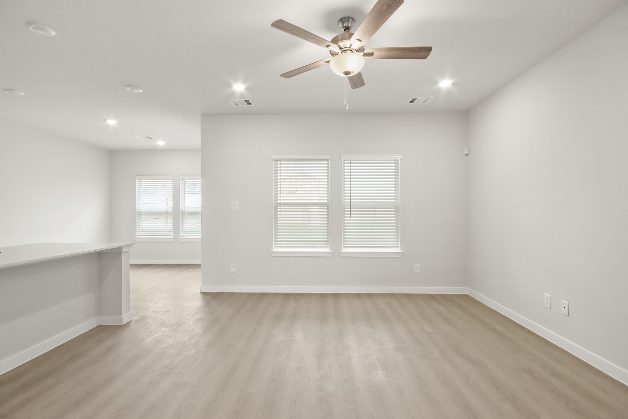 A room with a ceiling fan and a wood floor.