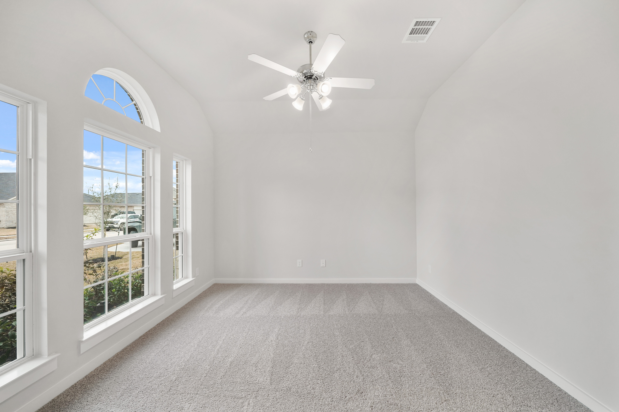 A room with a ceiling fan and windows.