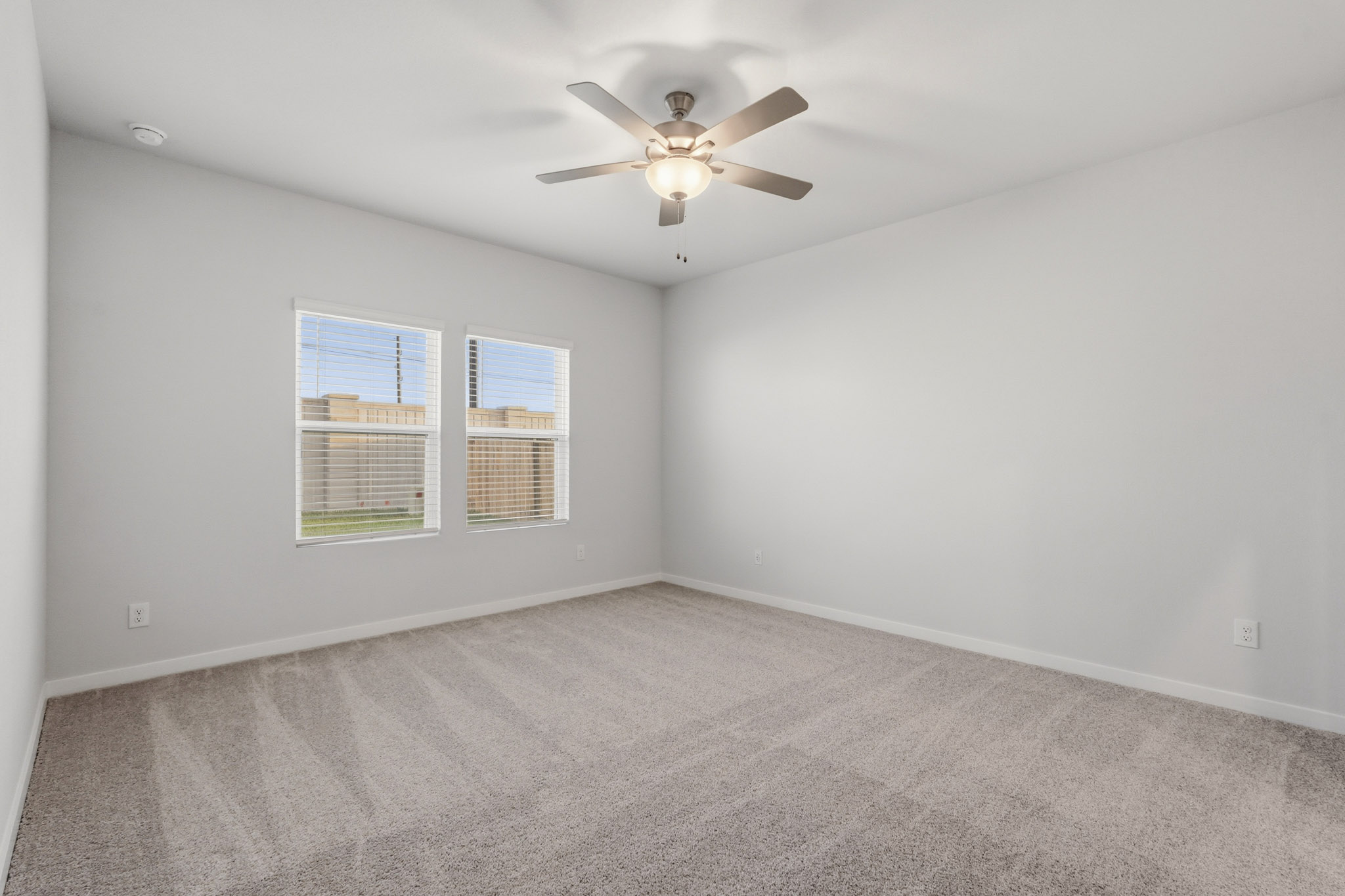 A room with a ceiling fan and a carpet.