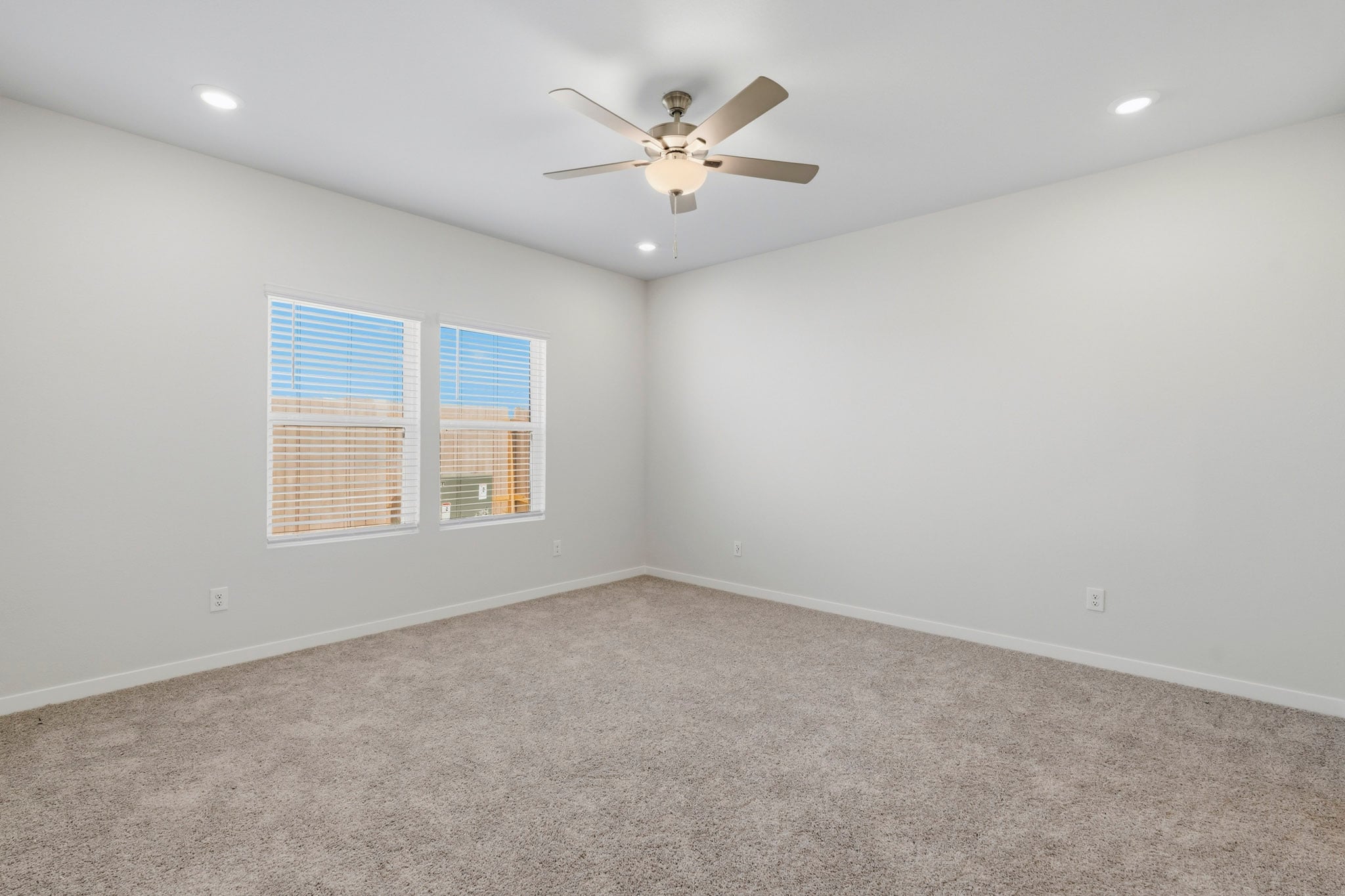 A room with a ceiling fan and a carpet.