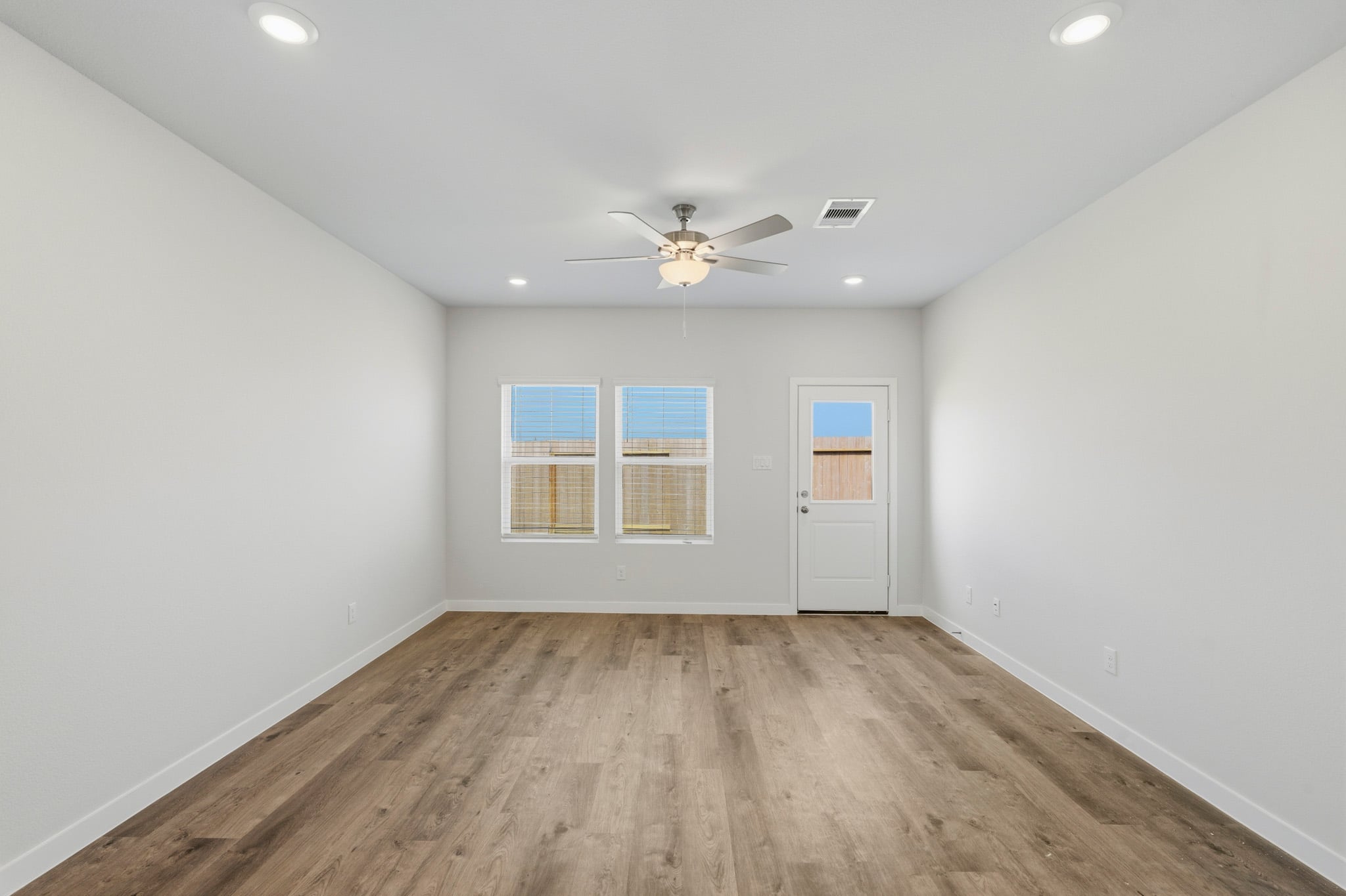 A room with a ceiling fan and a wood floor.