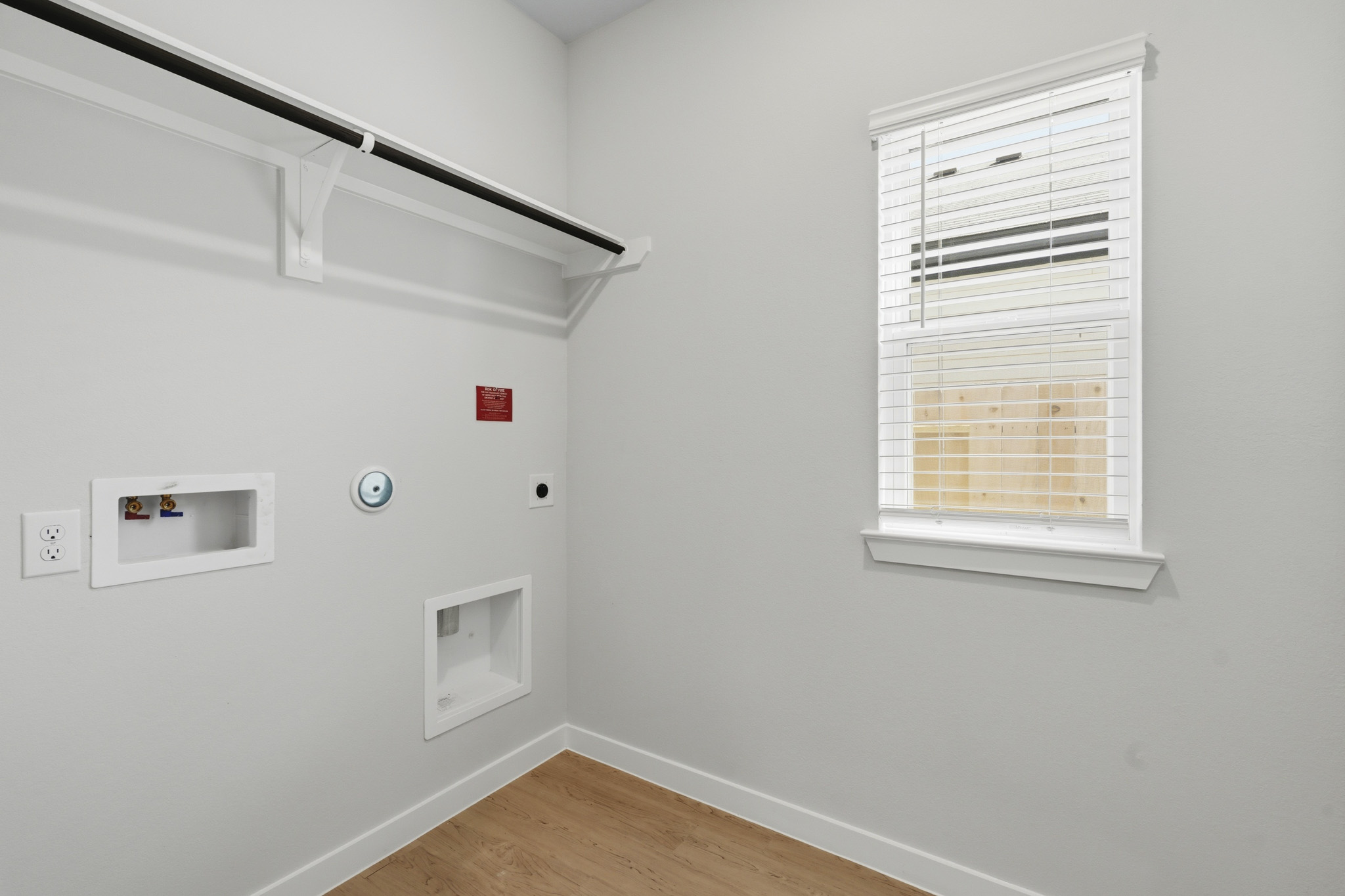 A white wall with a vent and a wood floor.