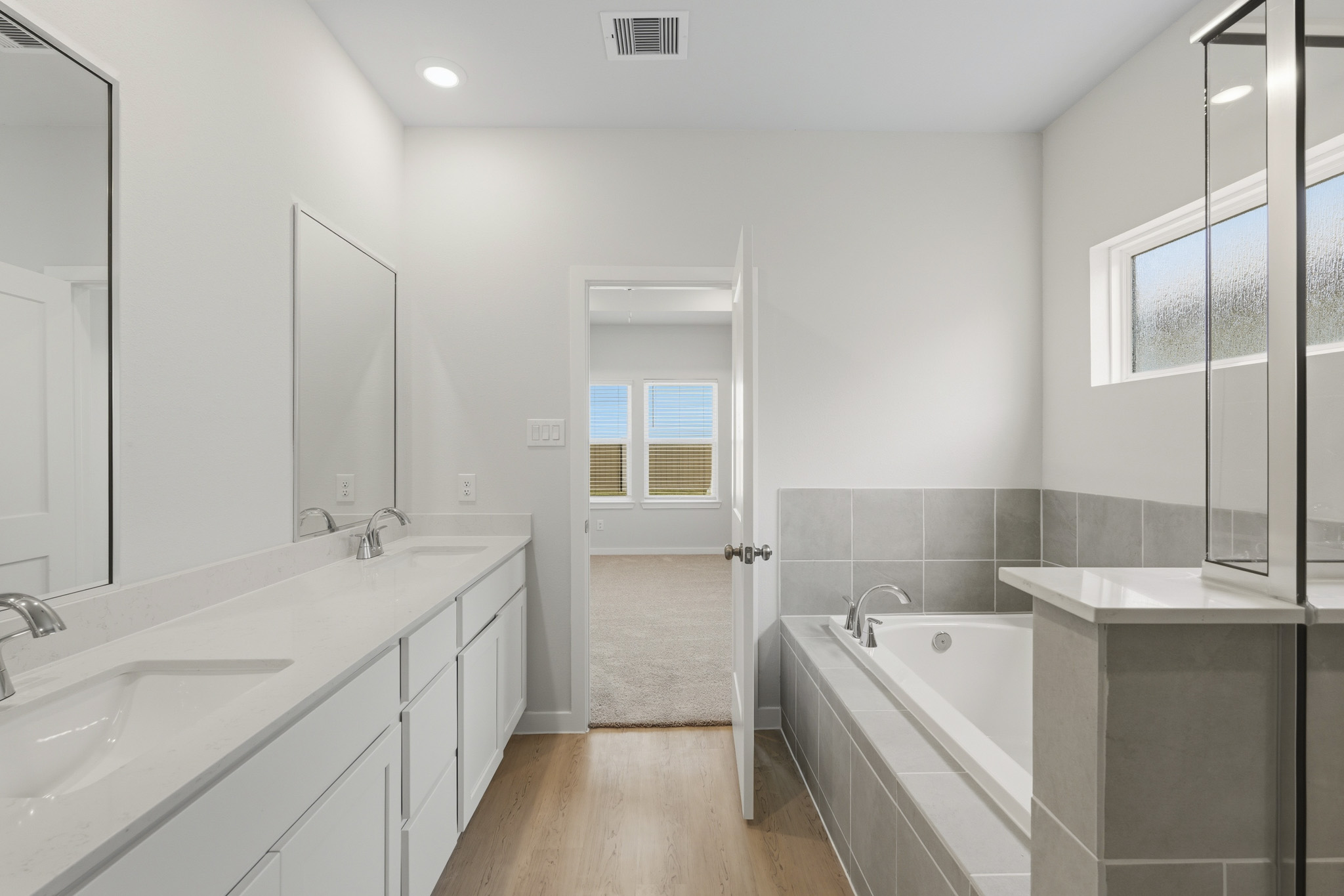 A bathroom with a tub sink and mirror.