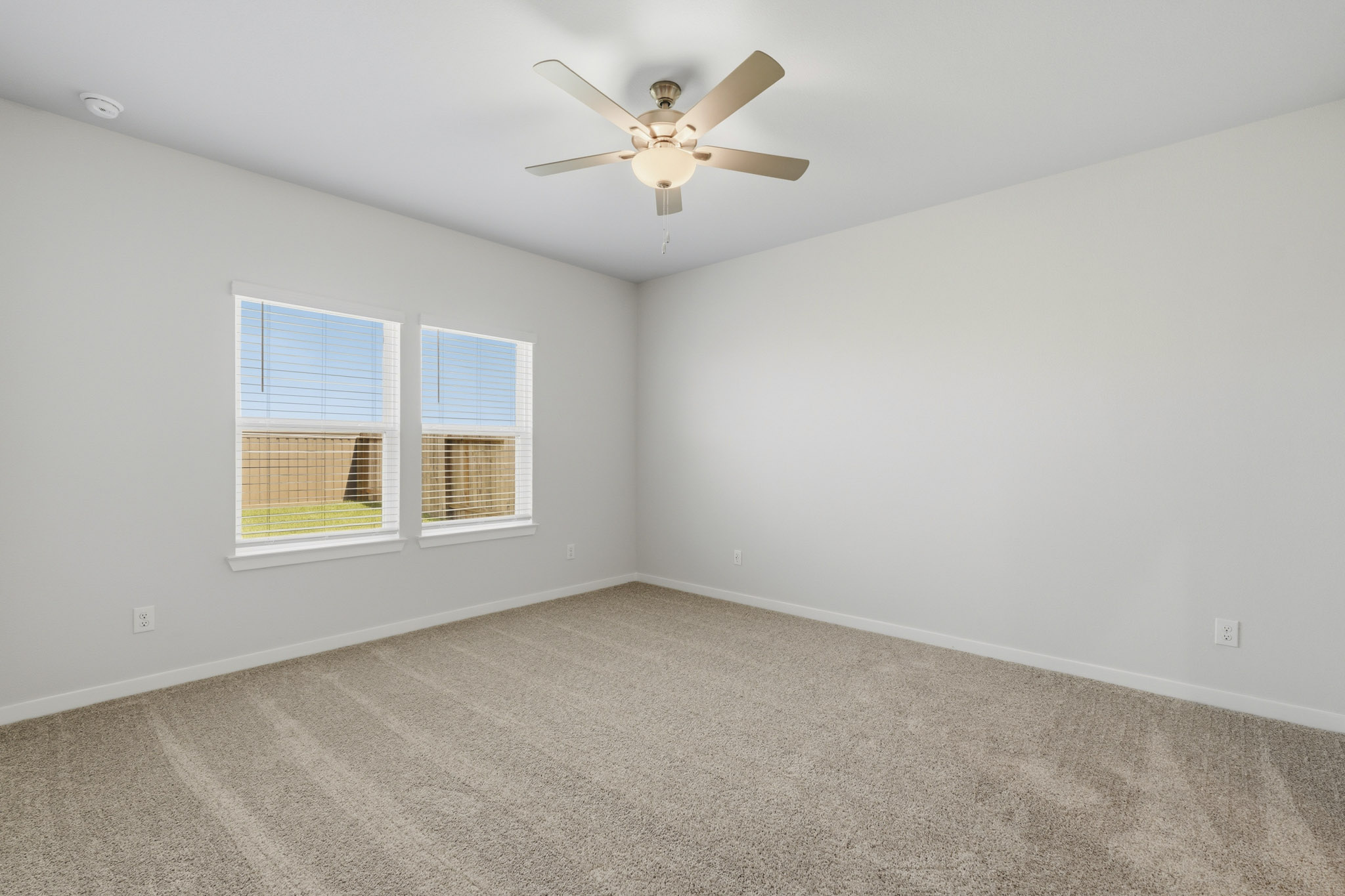 A room with a ceiling fan and a carpet.