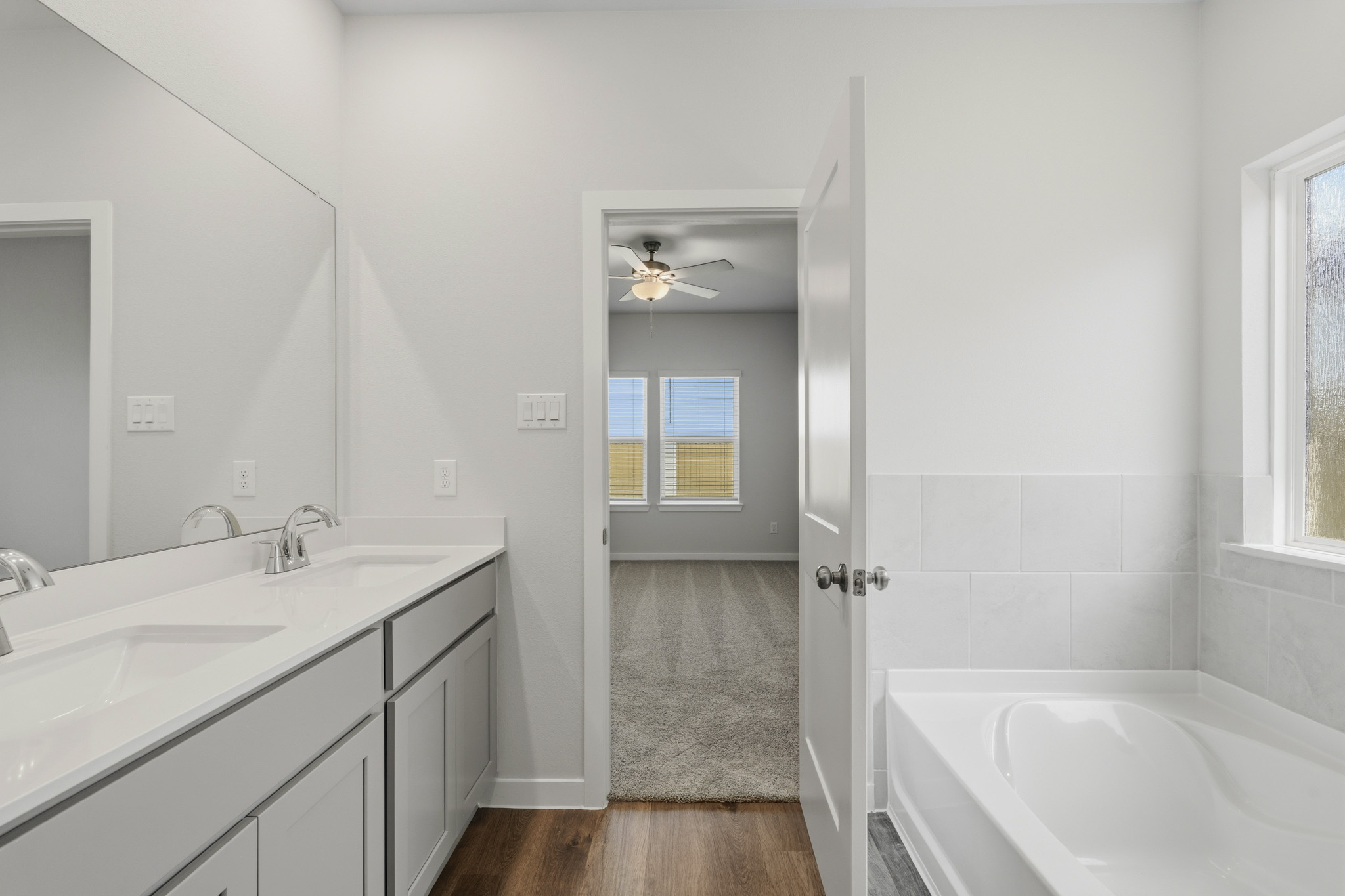 A bathroom with a tub sink and mirror.
