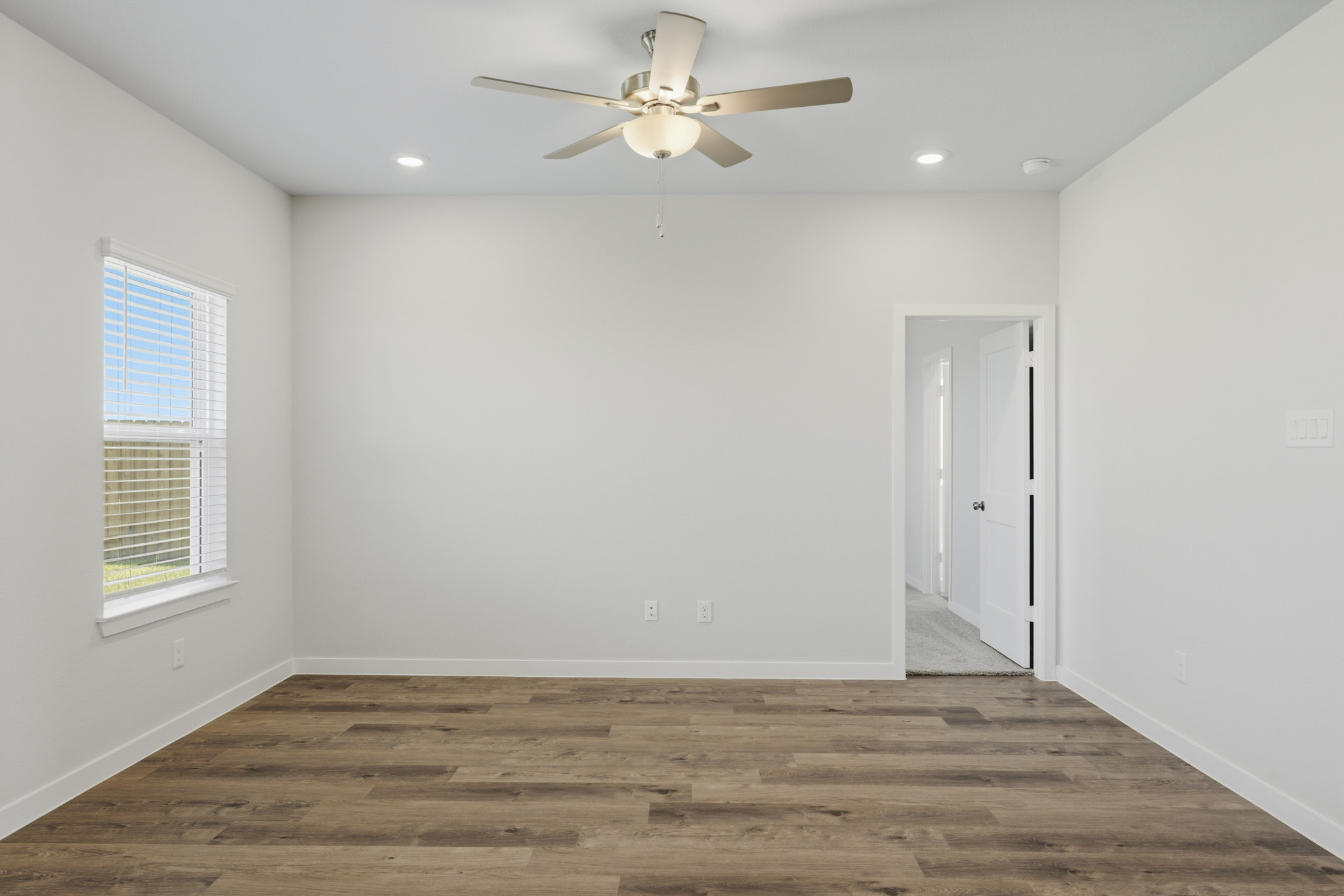 A room with a ceiling fan and a wood floor.
