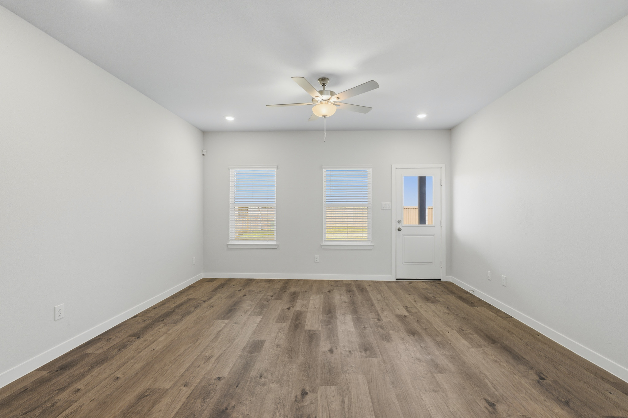 A room with a ceiling fan and a wood floor.