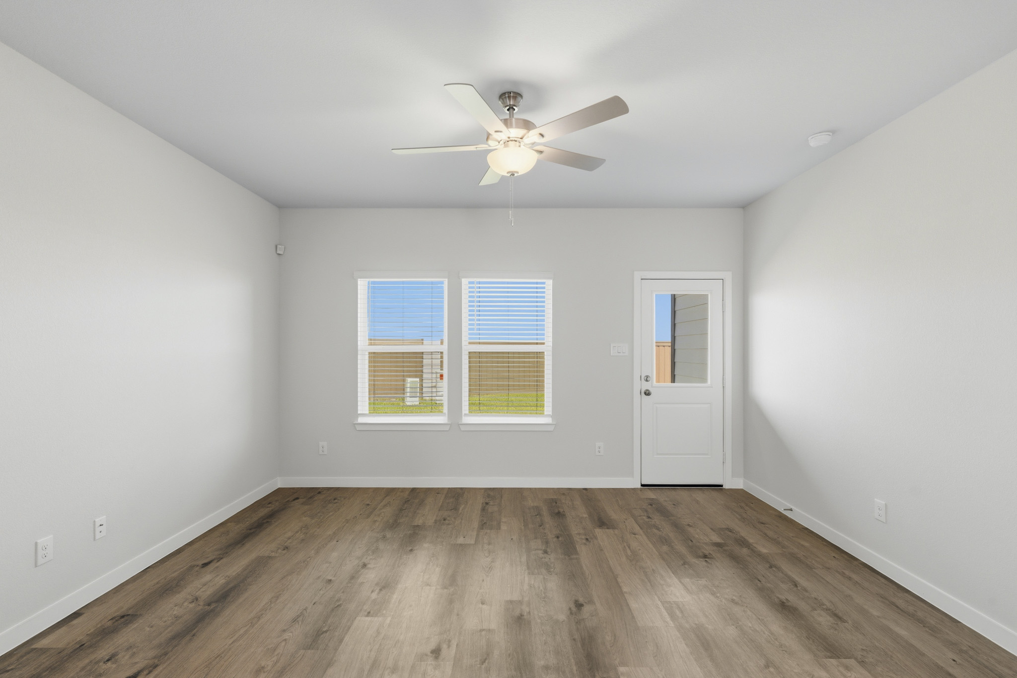 A room with a ceiling fan and a wood floor.