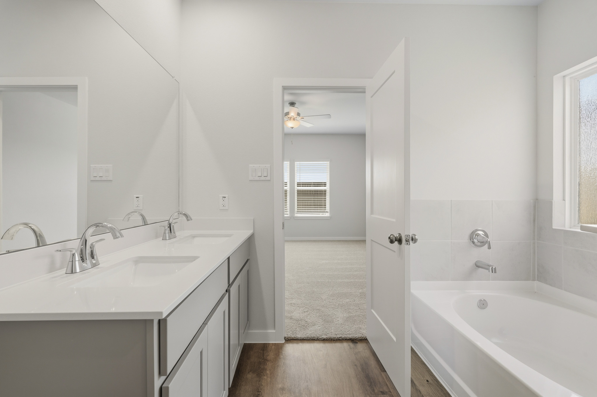 A bathroom with a tub sink and a mirror.