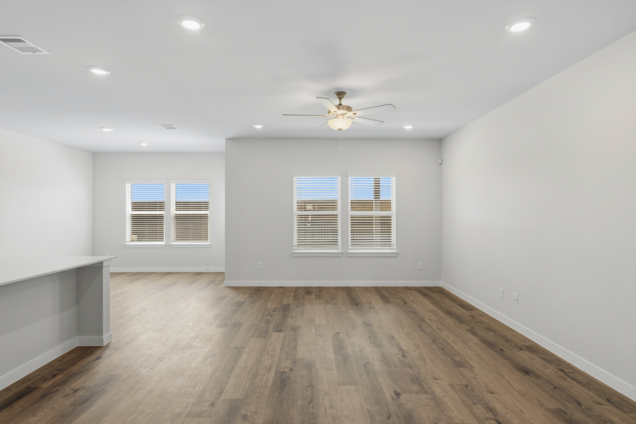 A room with a ceiling fan and a wood floor.