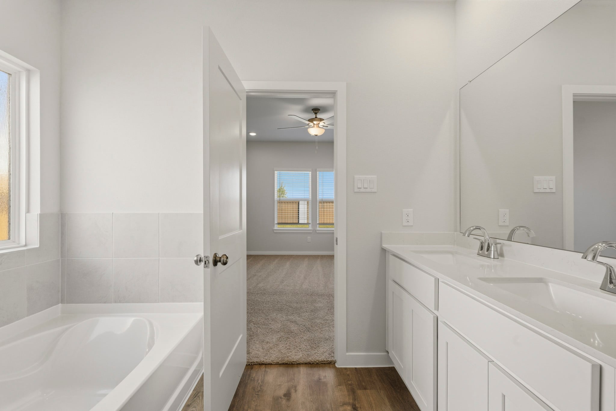 A bathroom with a tub sink and a mirror.