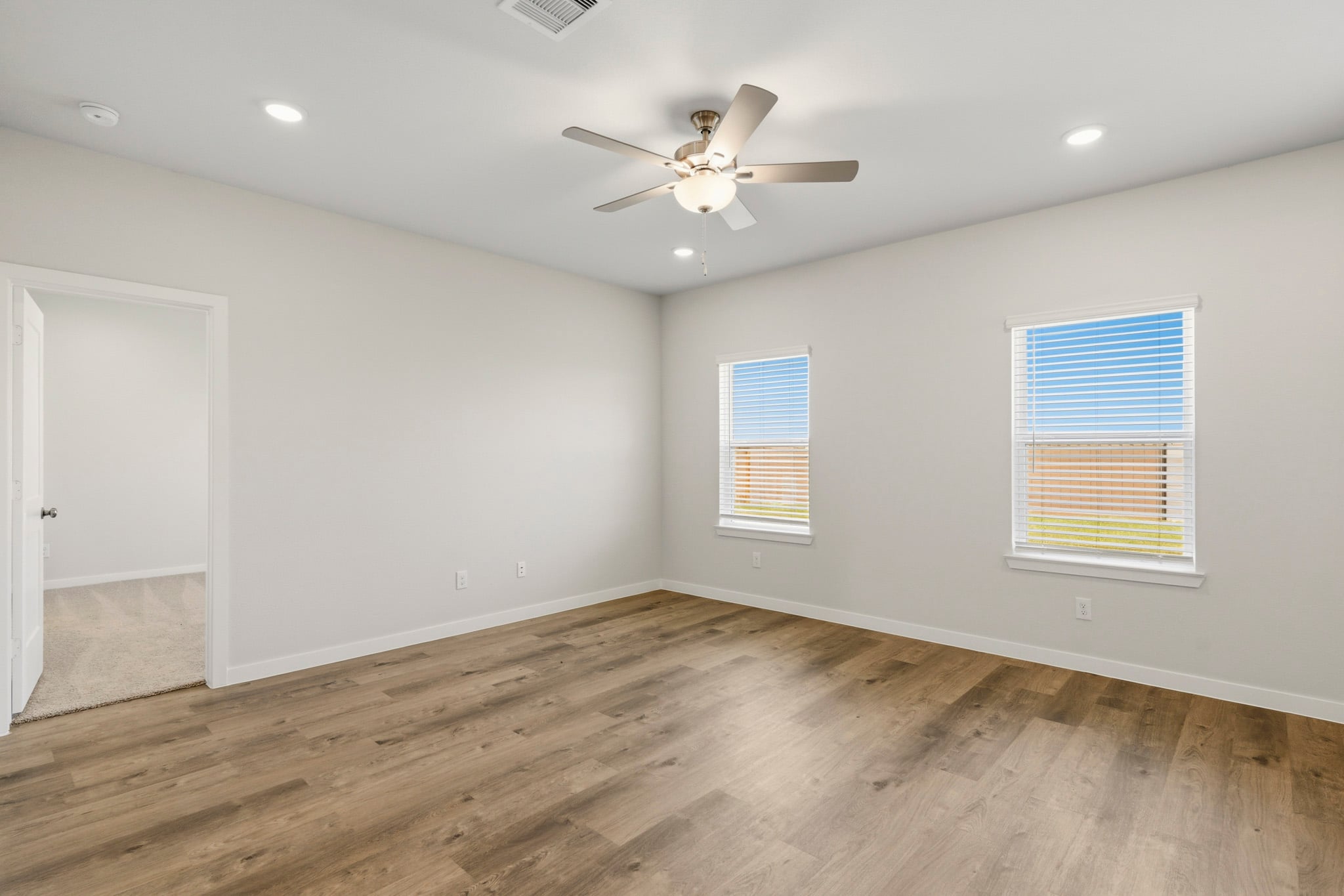 A room with a ceiling fan and wood floor.