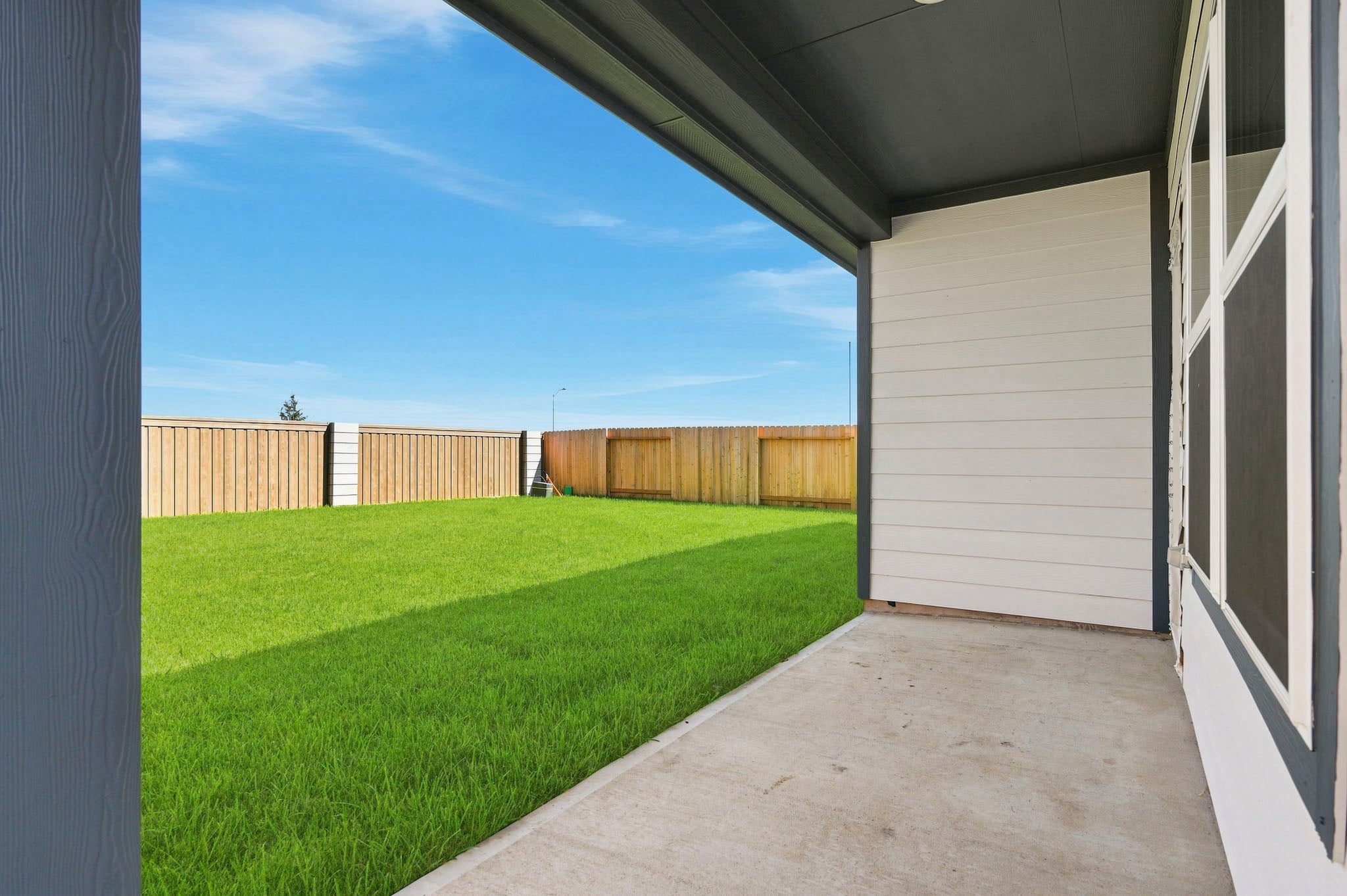 A backyard with a fence and grass.
